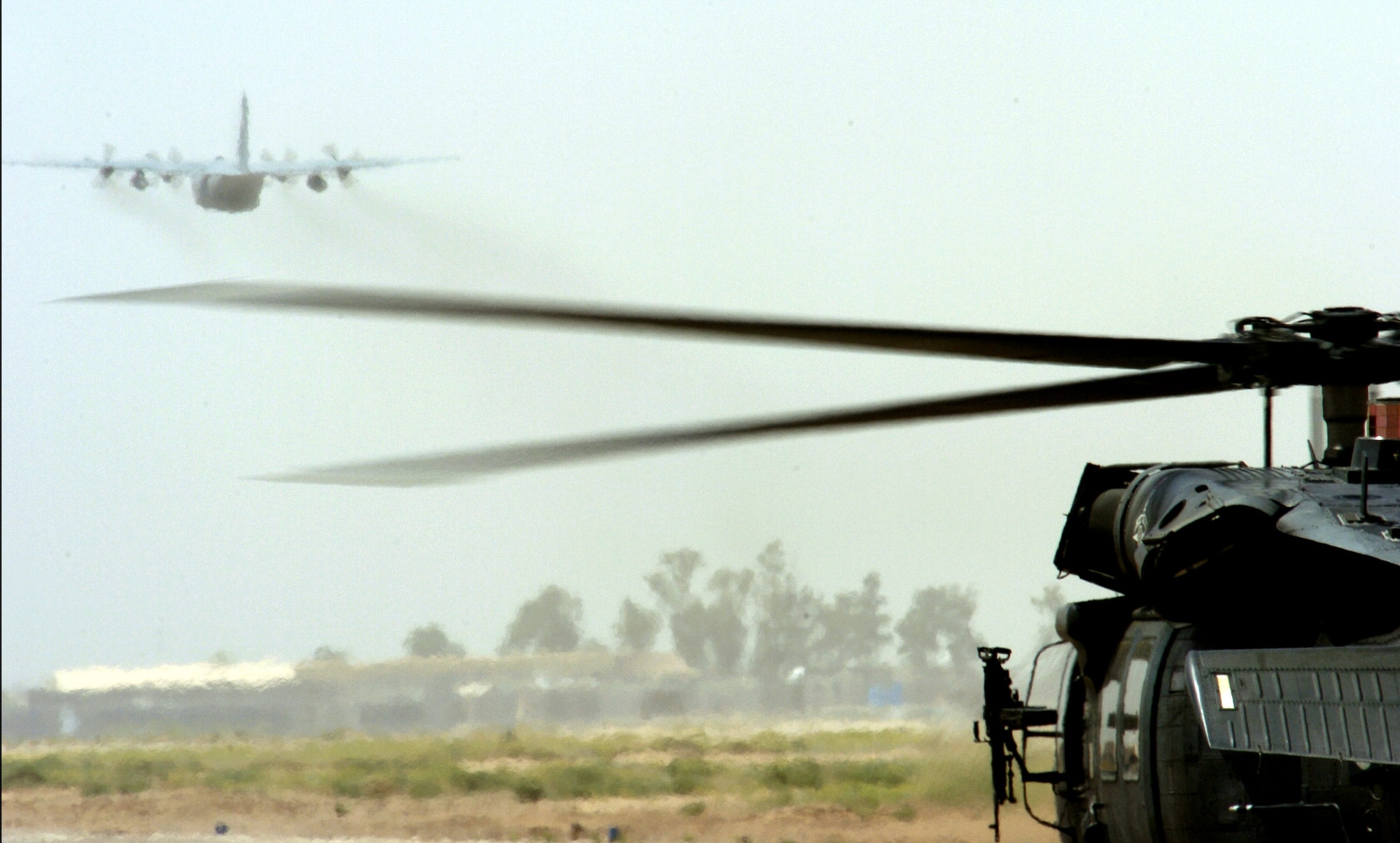 A C-130 Hercules takes off as a UH-60 Black hawk taxis past, at Balad Air Base, Iraq on May 17, 2006. The 777th Expeditionary Airlift Squadron has launched more than 3700 sorties that moved more than 54,200 people and 11,790 tons of cargo. The unit comprises active duty, Guard and Reserve aircraft and Airmen. (U.S. Air Force photo/Senior Airman Brian Ferguson) 
