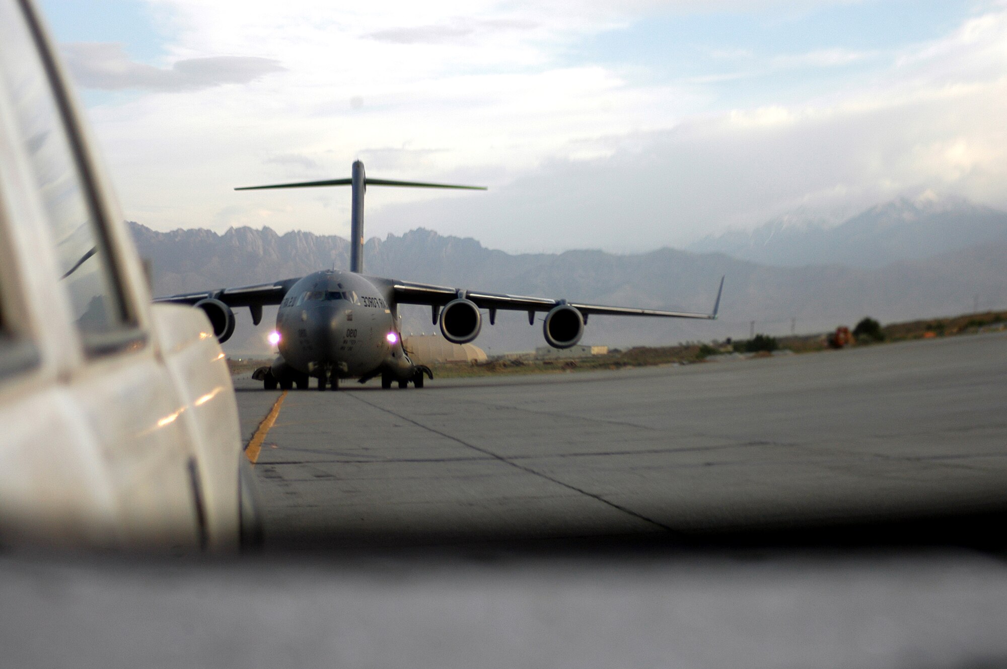 Seen in the rearview mirror of a "follow me" truck, a C-17 Globemaster III is guided to a parking spot at Bagram Air Base, Afghanistan, on Tuesday, May 16, 2006.  The transient alert section of the 455th Expeditionary Maintenance Squadron has the dubious task of finding parking spots for some 650 aircraft per month that fly cargo and passengers into the air base in support of Operation Enduring Freedom.  (U.S. Air Force photo/Maj. David Kurle)