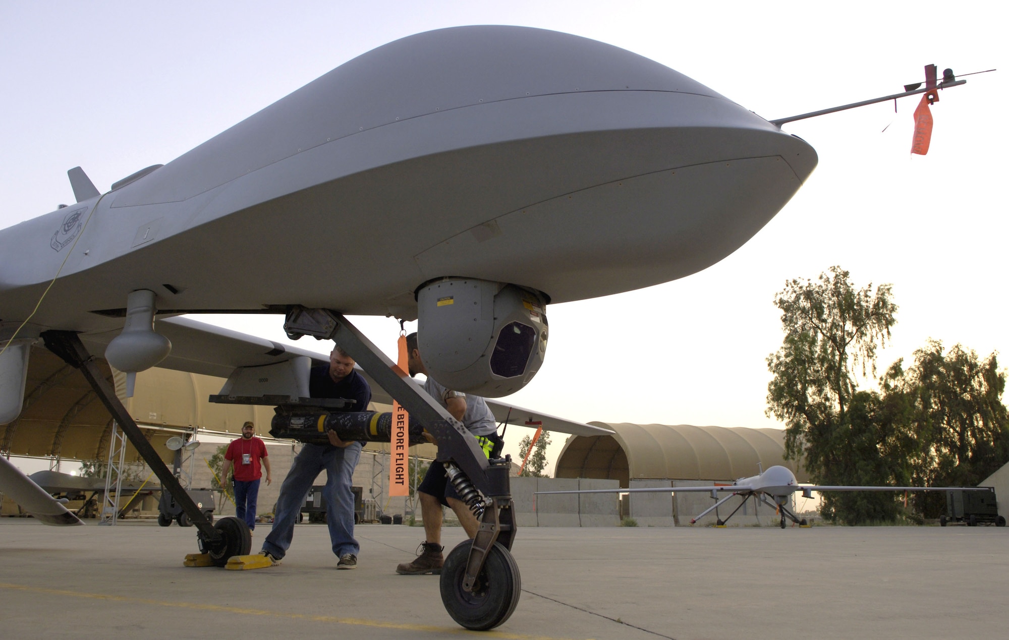 Joseph Stutzman and Robert Attard, contractors from General Atomics Aeronautical Systems, Inc., switch an AGM-114 Hellfire missile from one MQ-1 Predator to another on May 16, 2006, at Balad Air Base, Iraq.  Mr. Stutzman and Mr. Attard are aircraft mechanics assigned to the 46th Expeditionary Aircraft Maintenance Unit. Contractors began replacing some military maintainers in February 2006, and recently took over as the primary mechanics for the Predator.  (U.S. Air Force photo/Senior Airman Brian Ferguson)