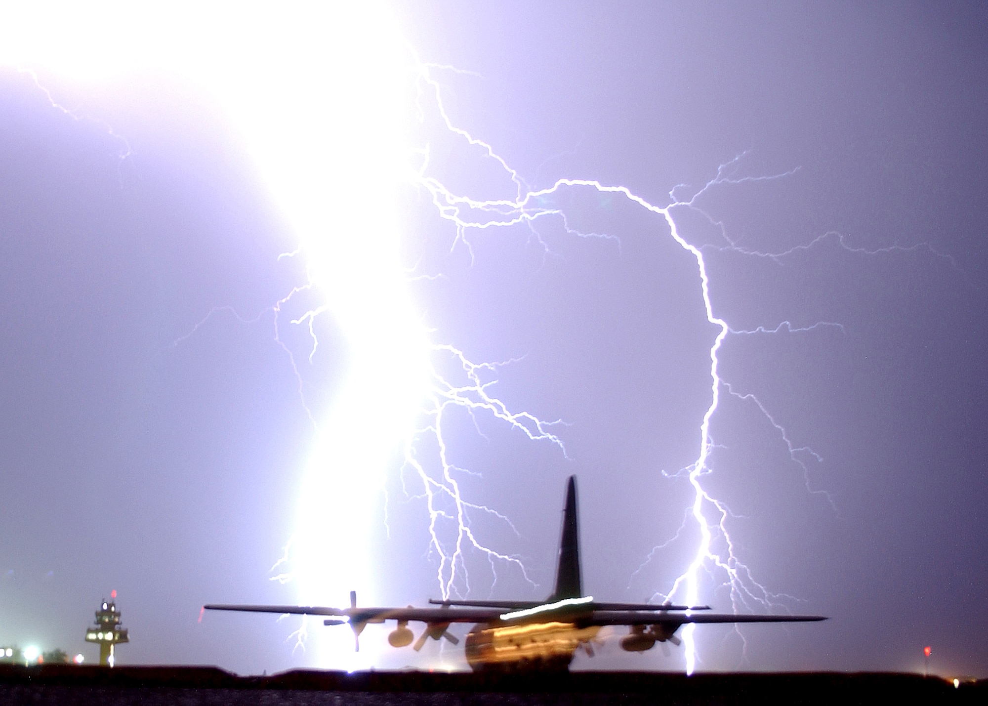 Lightning strikes near the control tower and a taxing C-130 Hercules at Balad Air Base, Iraq, on Tuesday, May 16, 2006. Balad handles more than 750 cargo flights each month and is the Department of Defense's busiest single runway. Using C-130s to fly in-theater airlift missions has reduced the number of ground convoys and troops exposed to roadside bomb attacks. (U.S. Air Force photo/Senior Airman James Croxon)                      