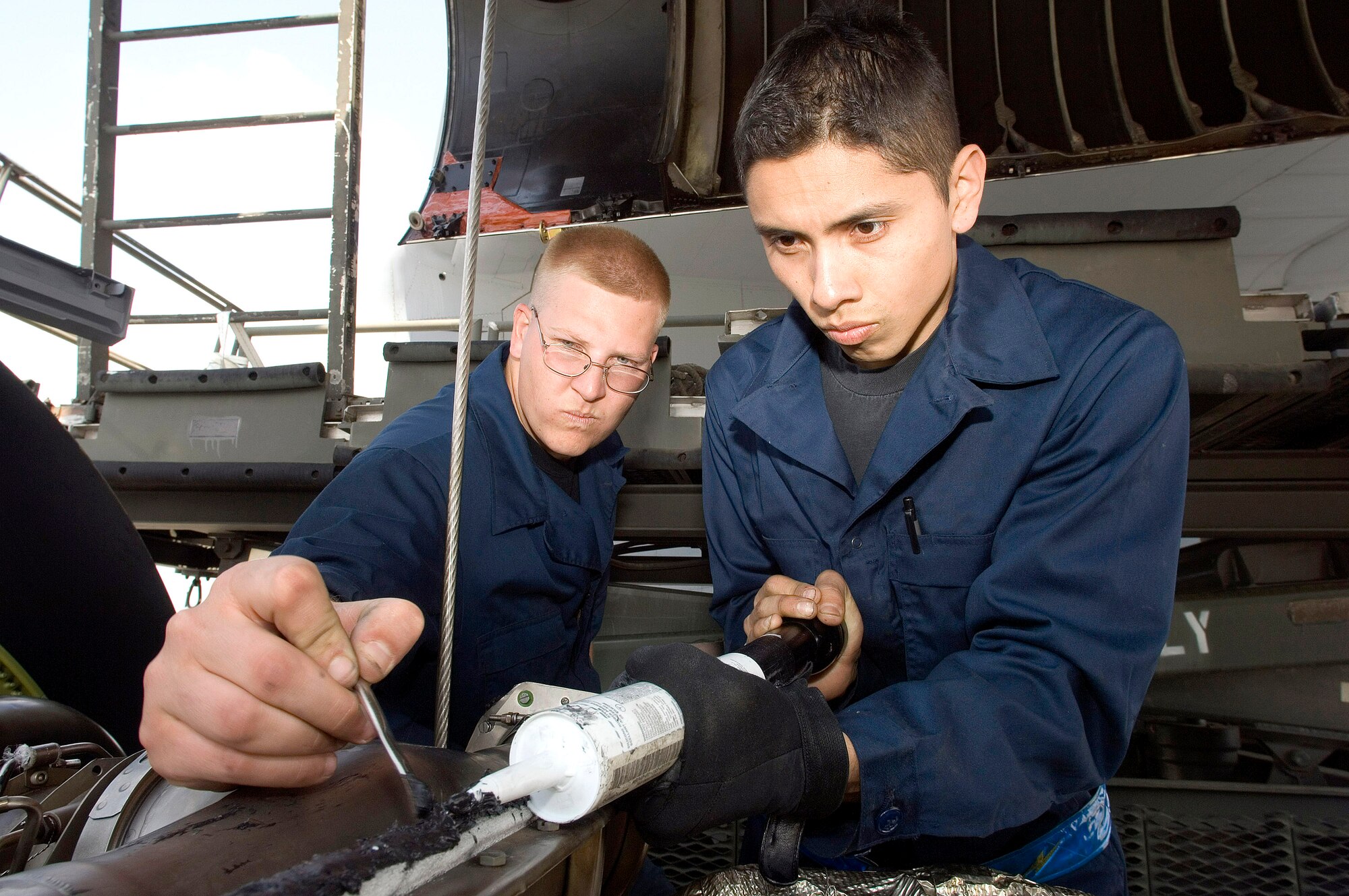 Senior Airmen Bryan McGee (left) and Jose Juarez put sealant in an engine as they prepare it for mounting on a C-5 Galaxy on May 12, 2006, at Ramstein Air Base Germany.  The Airmen are jet engine mechanics assigned to the 723rd Air Mobility Squadron.  (U.S. Air Force photo/Master Sgt. John E. Lasky) 