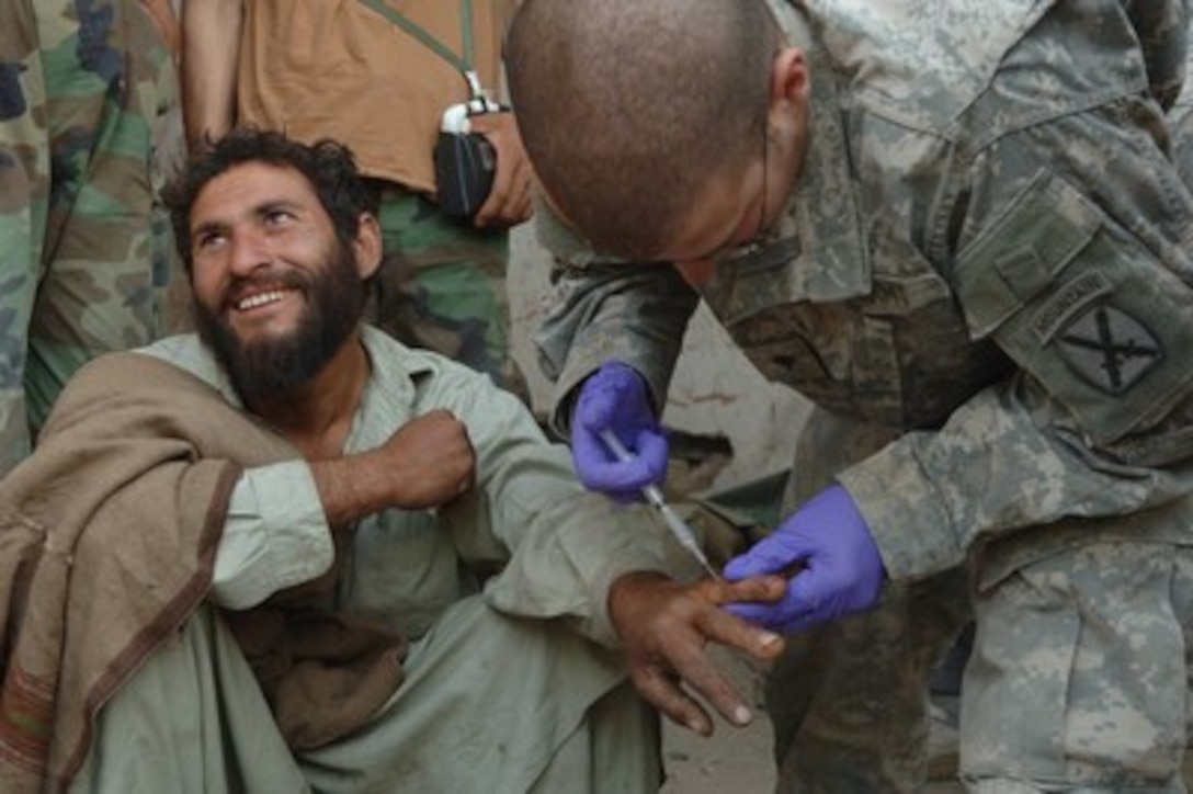 U.S. Army Spc. Joseph Angelo anesthetizes a local man's finger at Forward Operating Base Lumberyard in Afghanistan before suturing a laceration he received while working on May 7, 2006. Angelo is assigned to the 1st Battalion, 32nd Infantry Regiment. 