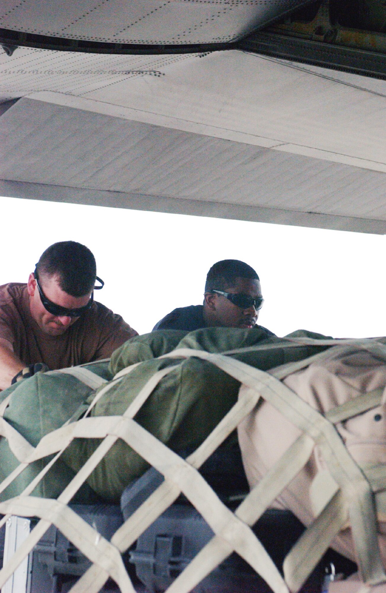 Staff Sgts. Joe Lankford (left) and Elston Robinson push a baggage pallet onto a C-130 Hercules on the ramp at Ali Base, Iraq.  The sergeants work in the Air Terminal Operations Center and are assigned to the 407th Expeditionary Logistics Readiness Squadron.  (U.S. Air Force photo/by Master Sgt. Andrew Gates) 