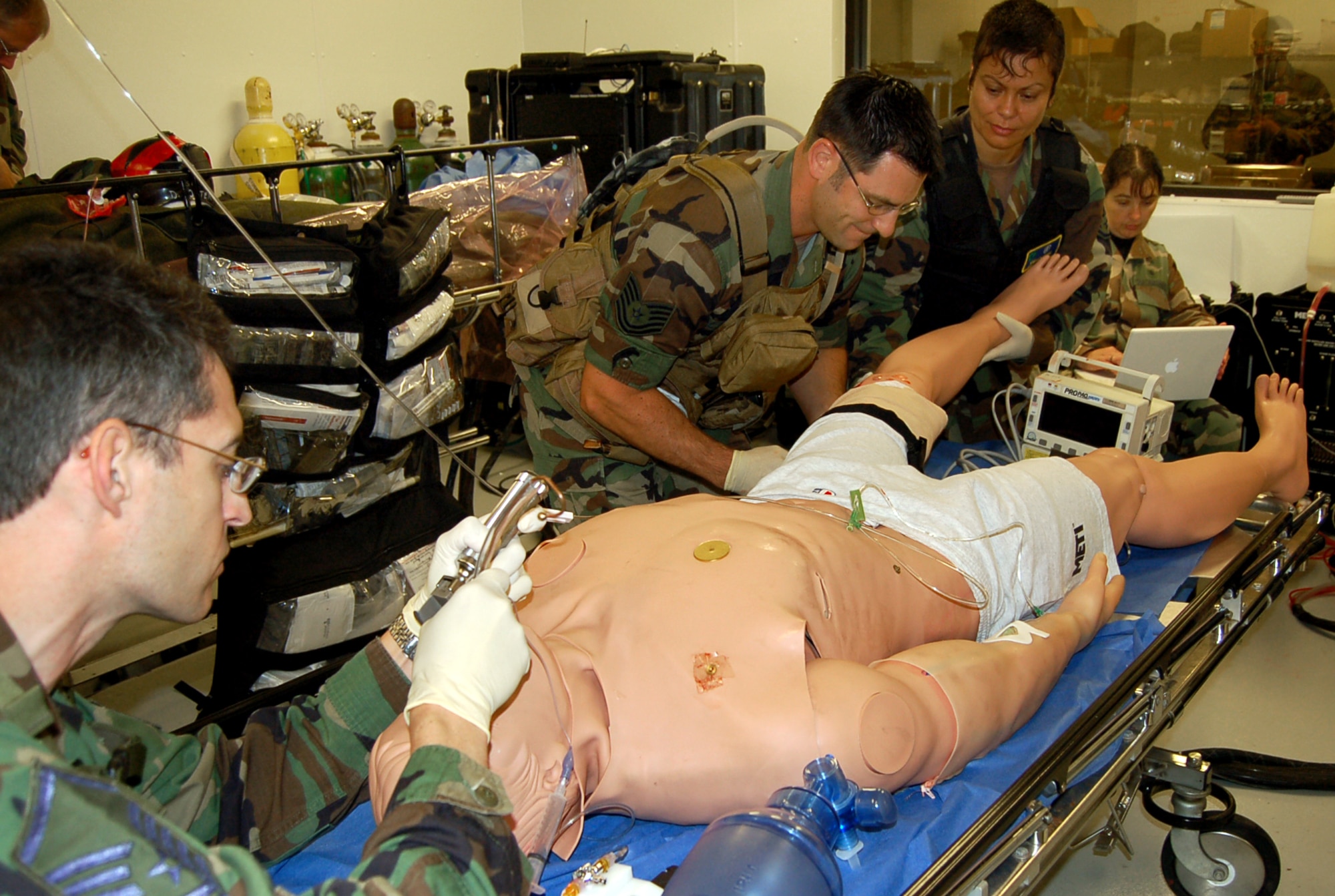 While Master Sgt. John Schiller (left) secures the airway on a computerized mannequin, Tech. Sgt Robert Carcieri and Staff Sgt. Suellen Carire begin to tend to a leg wound during a new Air Force Special Operations Command casualty evacuation course on Thursday, May 18, 2006.  The realistic training is geared to better prepare medics for the chaos of combat operations.  All three Airmen are from the 920th Rescue Wing, Patrick Air Force Base, Fla., and were among the first students to attend new course.  (U.S. Air Force photo/Master Sgt. Timothy P. Barela)