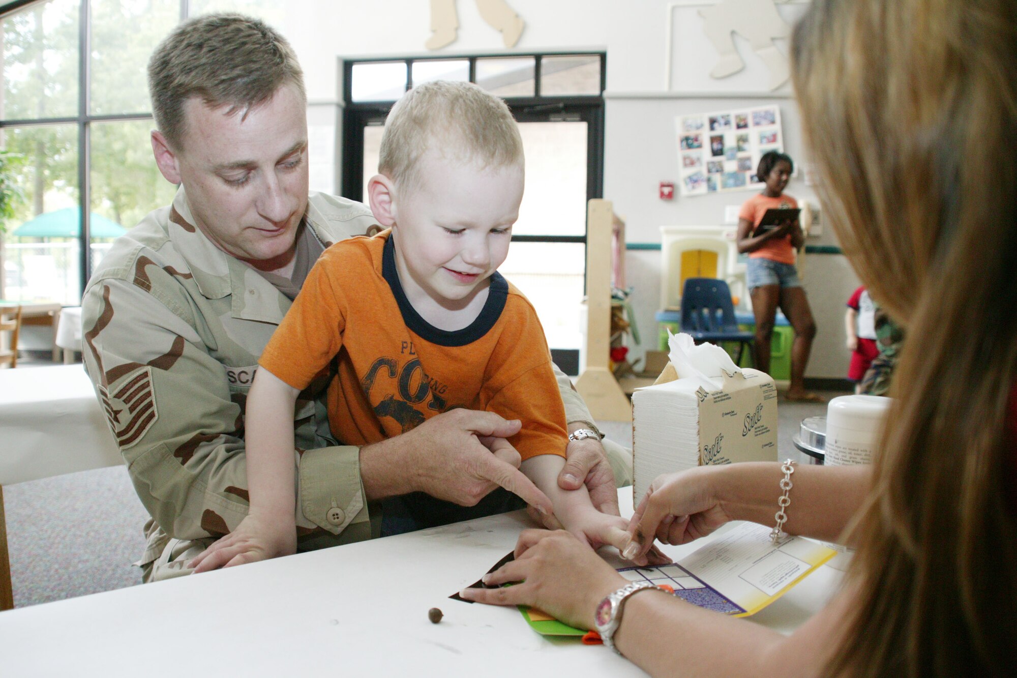 Greyson, son of Alyson and Tech. Sgt. Michael Scales, 609th Air Support Operations Squadron, gets finger printed by a security forces member for a child idenfication kit.  The kits are used to help identify or locate a missing child.  (U.S. Air Force Photo/Tarsha Storey)