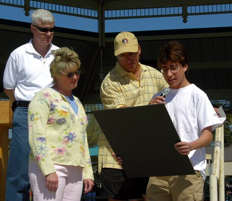 Keystone Club President and Hurlburt Field Youth of the Year Drake Sobania reads the Child Abuse Prevention Proclamation during the Hurlburt Field Family Fest April 15 in the Community Park. Col. Norman Brozenick Jr., 16th Special Operations Wing commander, and his wife, Lisa, look on while Jerry Romano, 16th Services Squadron, holds the microphone. April was declared the Child Abuse Prevention Month. (Photograph by Katrina Meyer)