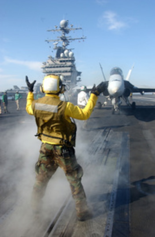 A U.S. Navy plane handler guides an F/A-18C Hornet aircraft to a catapult on the flight deck of the aircraft carrier USS Theodore Roosevelt (CVN 71) in preparation for launch on May 13, 2006. The Roosevelt is underway maintaining qualifications as part of the Navy's Fleet Response Plan. 