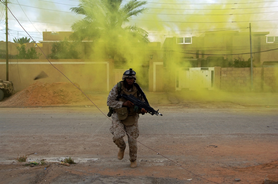 Camp Corregidor, Ramadi, Iraq. (May 20, 2006) A spent 5.56 mm brass casing flys past the camera as Corporal Christopher Kyle attached to 2nd Air Naval Gunfire Liaison Company (ANGLICO)  advances across a street under enemy fire to gain a better position to engage insurgents while on patrol in the city of Ramadi. The mission was part of the continuing support of the 2-28 BCT. 2-28 BCT is deployed with IMEF (FWD) in support of Operation Iraqi Freedom in the Al Anbar province of Iraq (MNF-W) to develop the Iraqi security forces, facilitate the development of official rule of law through democratic government reforms, and continue the development of a market based economy centered on Iraqi reconstruction. U.S Navy Photo by Photographers Mate Second Class Samuel C Peterson (Released)