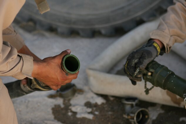 Teamwork pays off as two Marines with Combat Logistics Company 115, Combat Logistics Battalion 5, work to connect fuel lines May 20, 2006 in an effort to provide fuel to a forward operating base in the Fallujah area. In addition to providing fuel for American and Iraqi forces, the company provides other crucial supplies to service members in the Fallujah area; they have traveled in excess of 65,000 miles since arriving here three months ago.