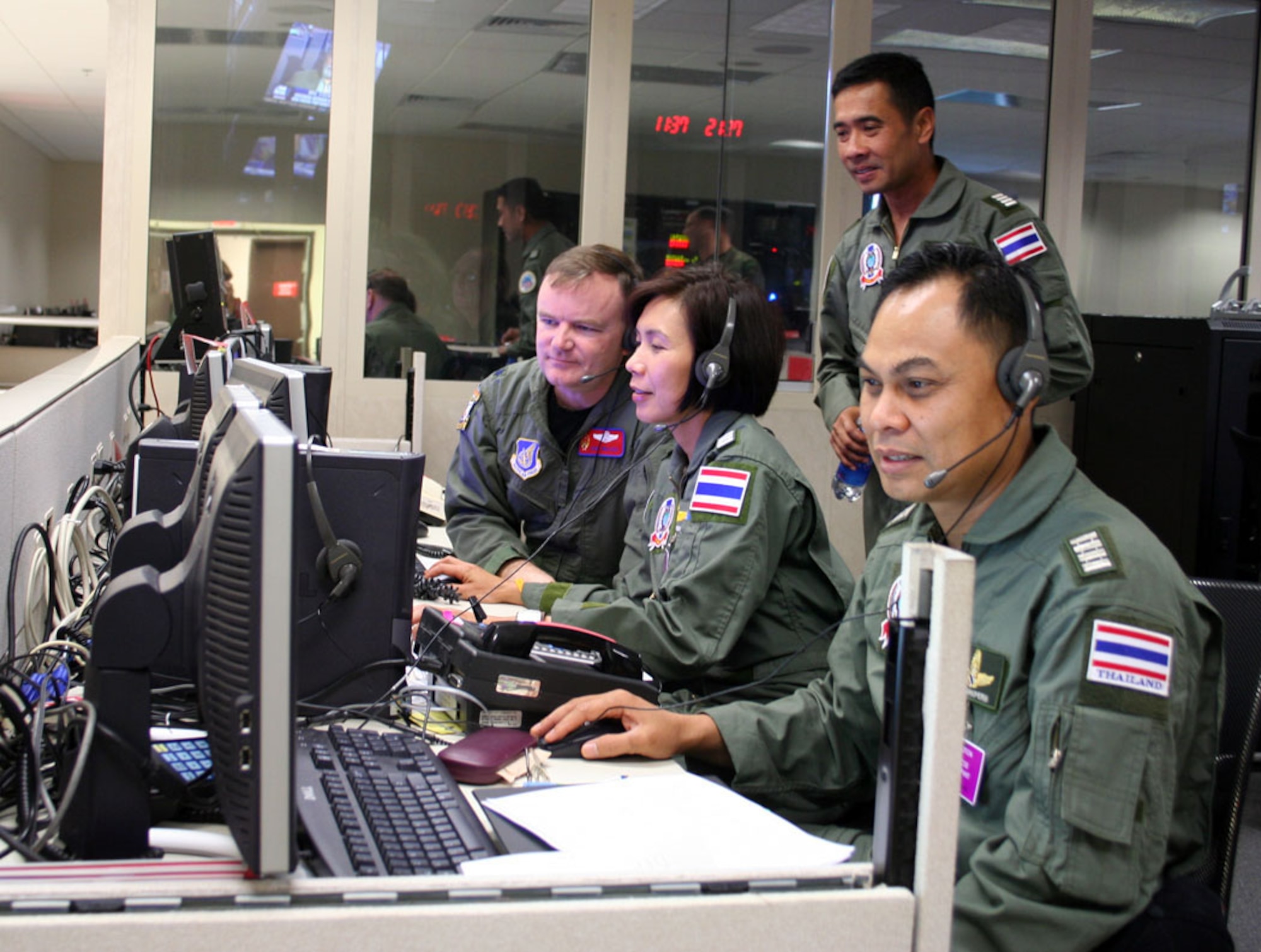 HICKAM AIR FORCE BASE, Hawaii -- Lt Col Curt Walker, Kenney Headquarters (13th Air Force) Pacific Air Operations Center, Combat Operations Division, and Wing Commander Sumana Chulamokha, Group Captain Suwit Wattanaroek (standing), and Group Captain Noi Parkperm from the Royal Thai Air Force coordinate air operations in KHQ's PAOC during the 25th annual Cobra Gold exercise hosted by Thailand. The exercise demonstrated the planning, execution and reach back capabilities KHQ can provide to the Combined Forces Air Component Commander during a joint and/or combined contingency. (Courtesy photo) 
