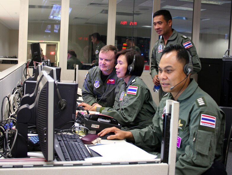 HICKAM AIR FORCE BASE, Hawaii -- Lt Col Curt Walker, Kenney Headquarters (13th Air Force) Pacific Air Operations Center, Combat Operations Division, and Wing Commander Sumana Chulamokha, Group Captain Suwit Wattanaroek (standing), and Group Captain Noi Parkperm from the Royal Thai Air Force coordinate air operations in KHQ's PAOC during the 25th annual Cobra Gold exercise hosted by Thailand. The exercise demonstrated the planning, execution and reach back capabilities KHQ can provide to the Combined Forces Air Component Commander during a joint and/or combined contingency. (Courtesy photo) 
