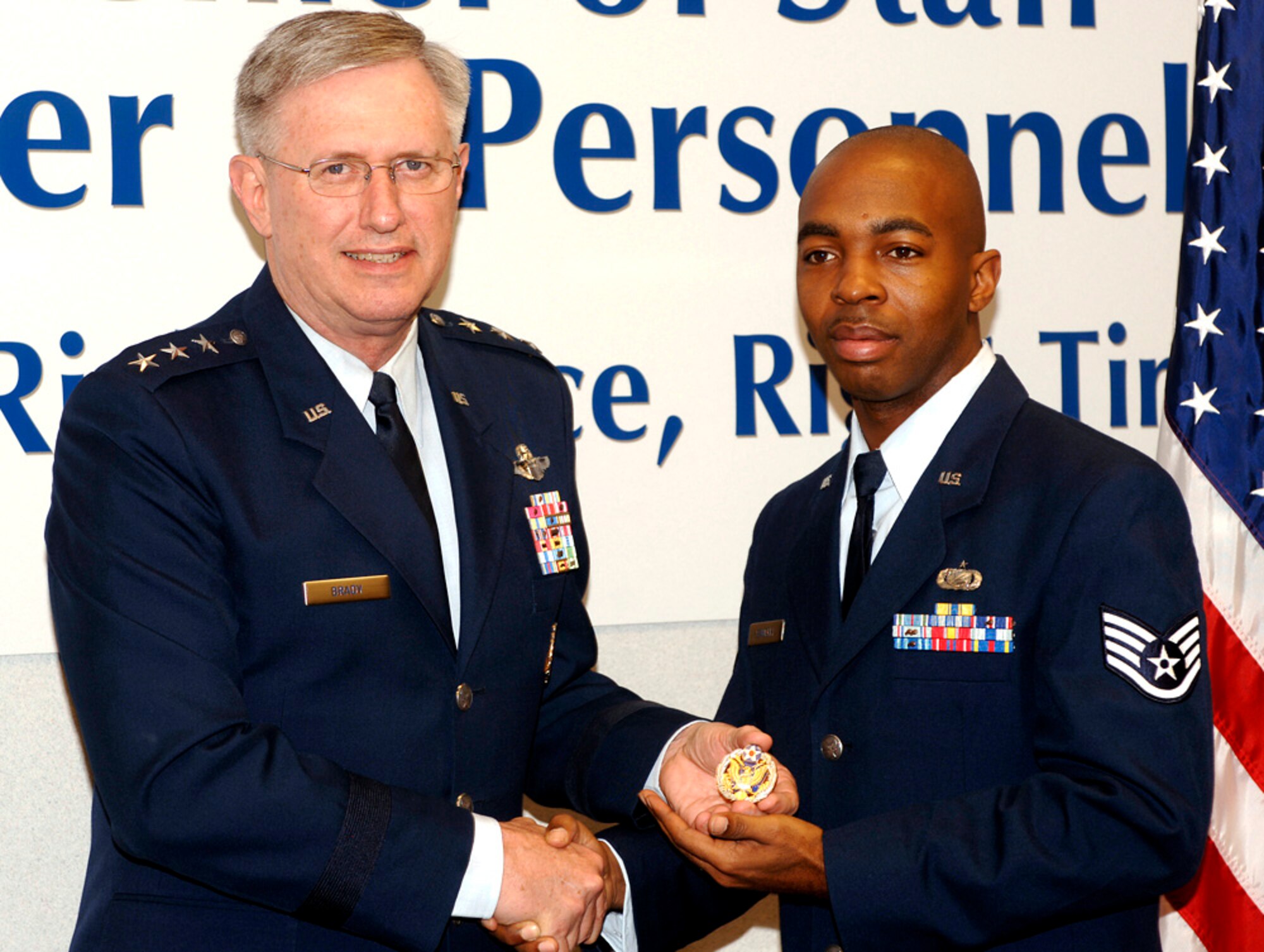Lt. Gen. Roger Brady, deputy chief of staff for manpower and personnel, presents the new Headquarters Air Force badge to Staff Sgt. Chris Kennerly during a ceremony marking the official release of the badge on Friday, May 19, 2006, in the Pentagon.  Airmen assigned to the Pentagon will have the option to wear the new badge.  The basis for the badge is Air Force heritage and the design incorporates many elements from the Department of the Air Force Seal.  Air Force Chief of Staff Gen. T. Michael Moseley approved the design and development of the badge in September.  (U.S. Air Force photo/Tech. Sgt. Scott M. Ash)