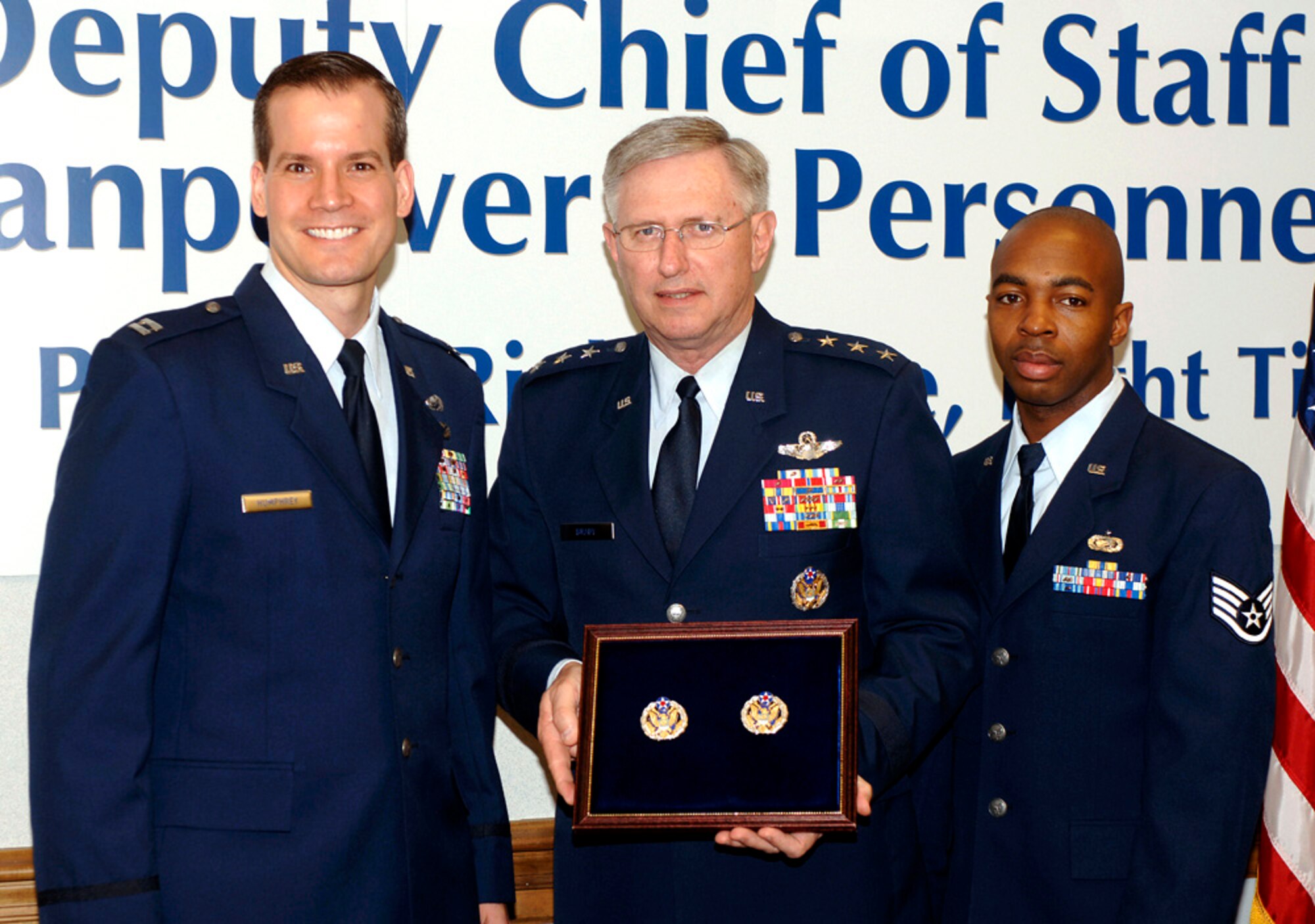 Lt. Gen. Roger Brady, deputy chief of staff for manpower and personnel, prepares to present a new Headquarters Air Force badge to Capt. Brian Humphrey and to Staff Sgt. Chris Kennerly during a ceremony marking the official release of the badge on Friday, May 19, 2006, in the Pentagon.  Airmen assigned to the Pentagon will have the option to wear the new badge.  The basis for the badge is Air Force heritage and the design incorporates many elements from the Department of the Air Force Seal.  Air Force Chief of Staff Gen. T. Michael Moseley approved the design and development of the badge in September.  (U.S. Air Force photo/Tech. Sgt. Scott M. Ash)