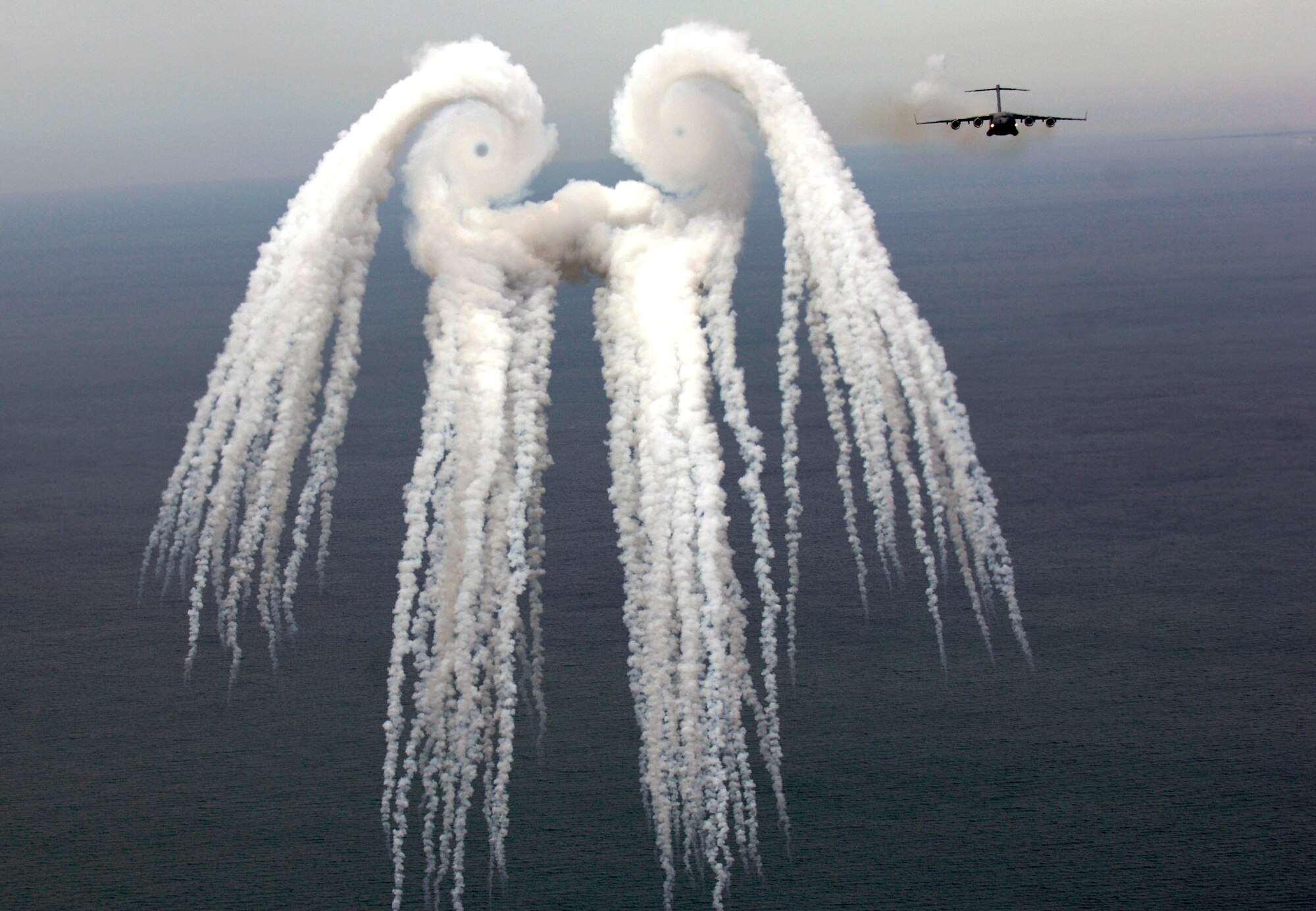 A C-17 Globemaster III from the 14th Airlift Squadron, Charleston Air Force Base, S.C. releases flares over the Atlantic Ocean near Charleston, S.C., during a training mission on Tuesday, May 16, 2006.  The "smoke angel" is caused by the vortex from the engines.  (U.S. Air Force photo/Tech. Sgt. Russell E. Cooley IV)