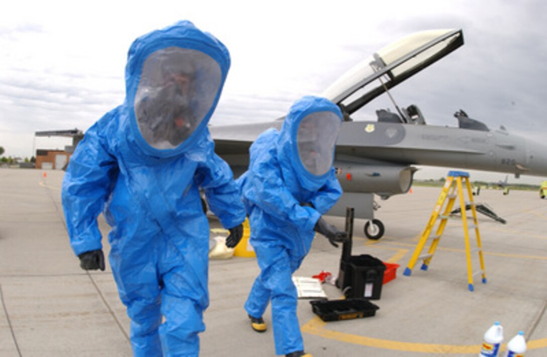U.S. Air Force Staff Sgt. Lee T. Teigen (left) and Tech. Sgt. Daniel C. Grimestad wear personal protective equipment as they practice cleaning up a simulated hazardous material spill under an F-16 Fighting Falcon aircraft during a training exercise at the North Dakota Air National Guard, Fargo, N.D., on May 18, 2006. Teigen and Grimestad are attached to the 119th Maintenance Squadron. 