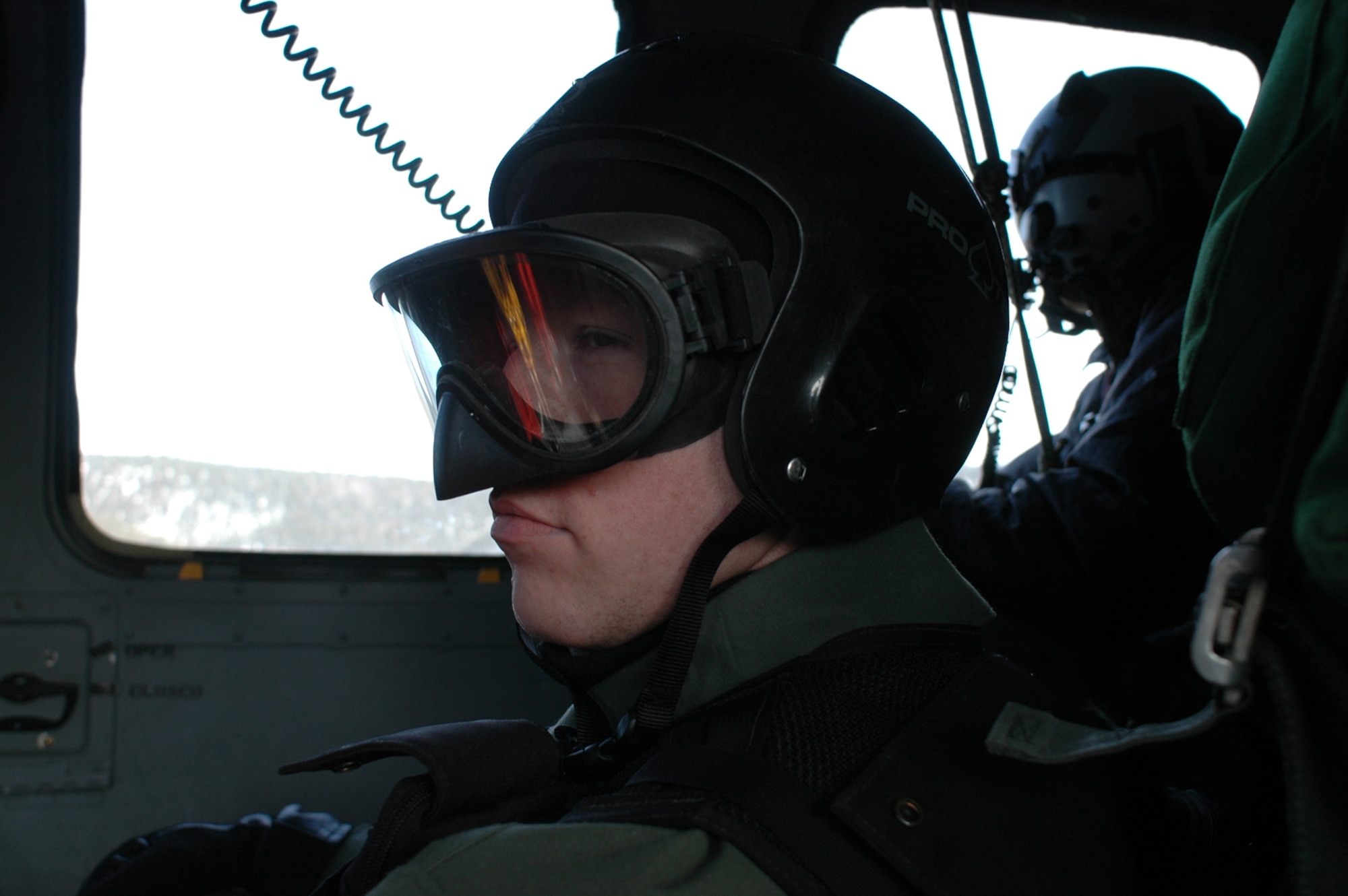 EIELSON AIR FORCE BASE, Alaska - Capt. Ryan "Olaf" Pumford, F-16 pilot, 18th Fighter Squadron here, sits motionless in a Pavehawk helicopterafter being rescued by members of the 210th Rescue Squadron, Kulis Air National Guard Base, Alaska, as an unidentified PJ (pararescueman) watches the terrain below for threats to the helicopter.  All are players involved in a combat search and rescue training exercise. during RED FLAG - Alaska 06-2. (Air Force Photo by Tech. Sgt. Jeff Walston)