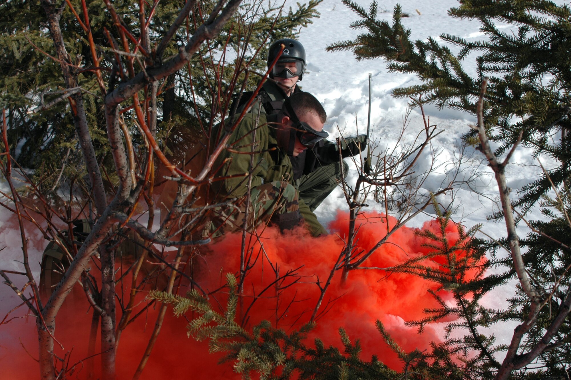 EIELSON AIR FORCE BASE, Alaska - Staff Sgt. Marc Richard, SERE Specialist, 353rd Combat Training Squadron, Detachment One, Elmendorf AFB, Alaska, pops red smoke as Capt. Ryan "Olaf" Pumford, F-16 pilot, 18th Fighter Squadron here, watches for the recovery vehicle from the 210th Rescue Squadron, Kulis Air National Guard Base, Alaska, to pick him up. All are players involved in a combat search and rescue training exercise here May 2, 2006, during RED FLAG - Alaska 06-2.  (Air Force photo by Tech. Sgt. Jeff Walston)
