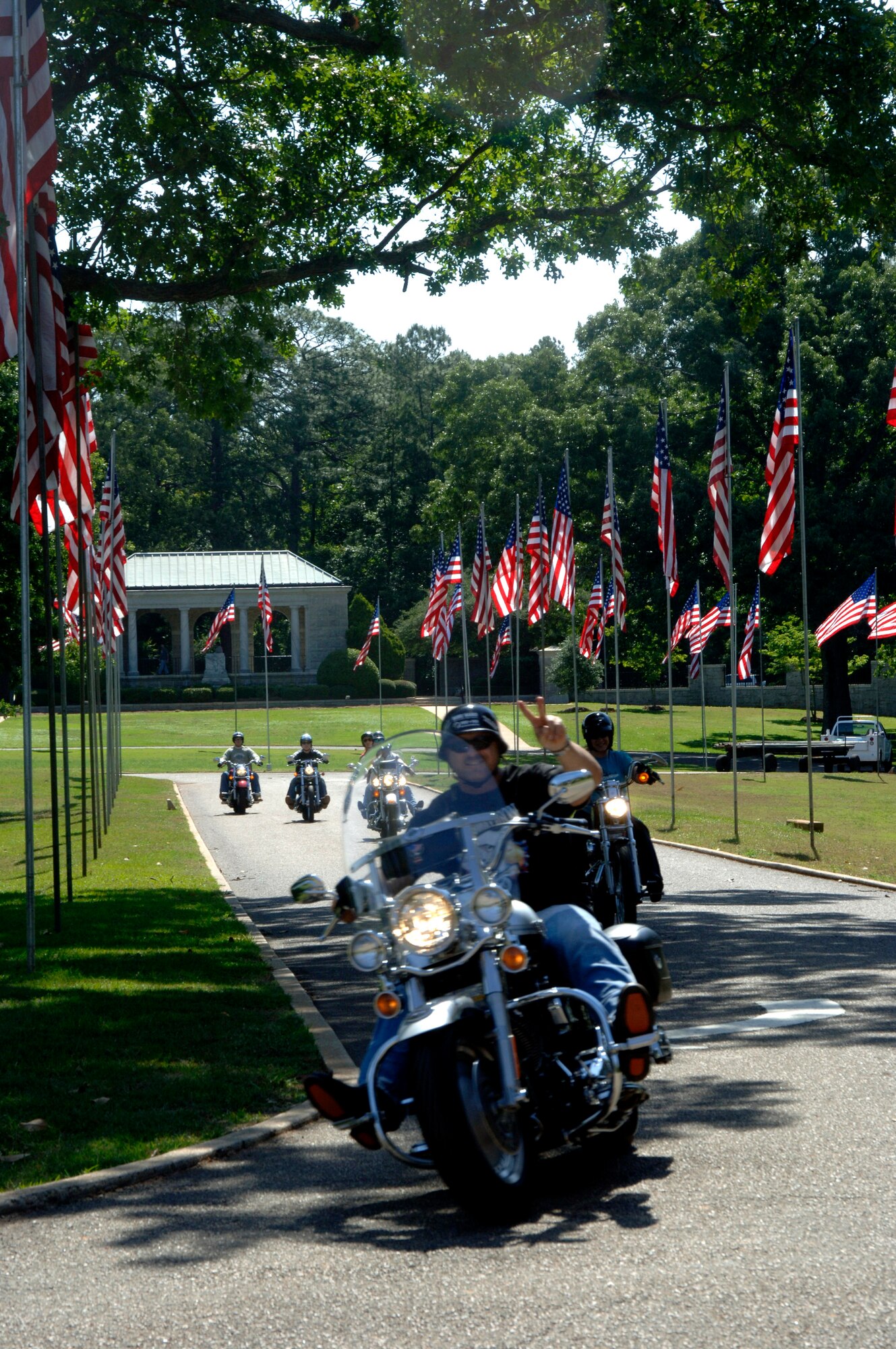 Motorcyclists from Robins Air Force Base, Ga., who set up U.S. flags at Andersonville National Cemetery near Americus, Ga., on Friday, May 19, 2006, head home with their handiwork waving in the background.  The group of 70 motorcycle enthusiasts rode as a convoy on the 50-mile trip to set up the flags for Memorial Day.  (U.S. Air Force photo/Senior Master Sgt. Tom McKenzie) 