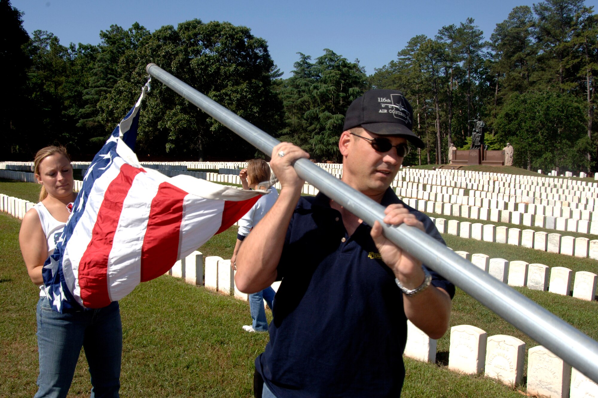 First Lt. Tiffany Changet and Master Sgt. Randall Miller set up a U.S. flag at Andersonville National Cemetery near Americus, Ga., on Friday, May 19, 2006. They were part of a group of 70 motorcycle enthusiasts from Robins Air Force Base, Ga., who volunteered to set up U.S. flags for Memorial Day. The group rode as a convoy on the 50-mile trip. Lieutenant Changet and Sergeant Miller are with the 116th Air Control Wing. (U.S. Air Force photo/Senior Master Sgt. Tom McKenzie) 