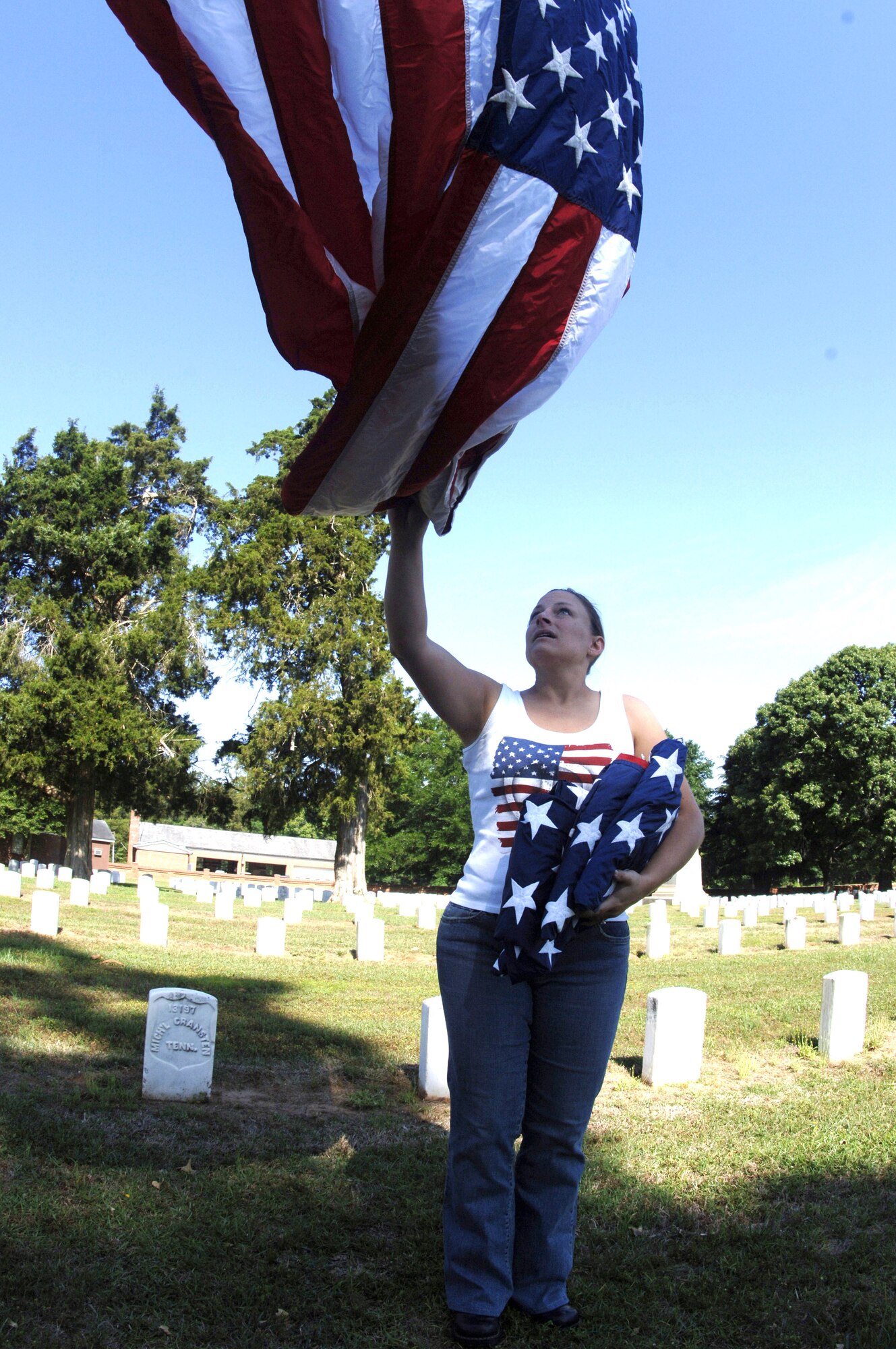 First Lt. Tiffany Changet unfurls a U.S. flag at Andersonville National Cemetery near Americus, Ga., on Friday, May 19, 2006.  She was one of 70 motorcycle enthusiasts from Robins Air Force Base, Ga., who volunteered to set up U.S. flags for Memorial Day.  The group rode as a convoy on the 50-mile trip.  Lieutenant Changet is with the 116th Air Control Wing. (U.S. Air Force photo/Senior Master Sgt. Tom McKenzie) 