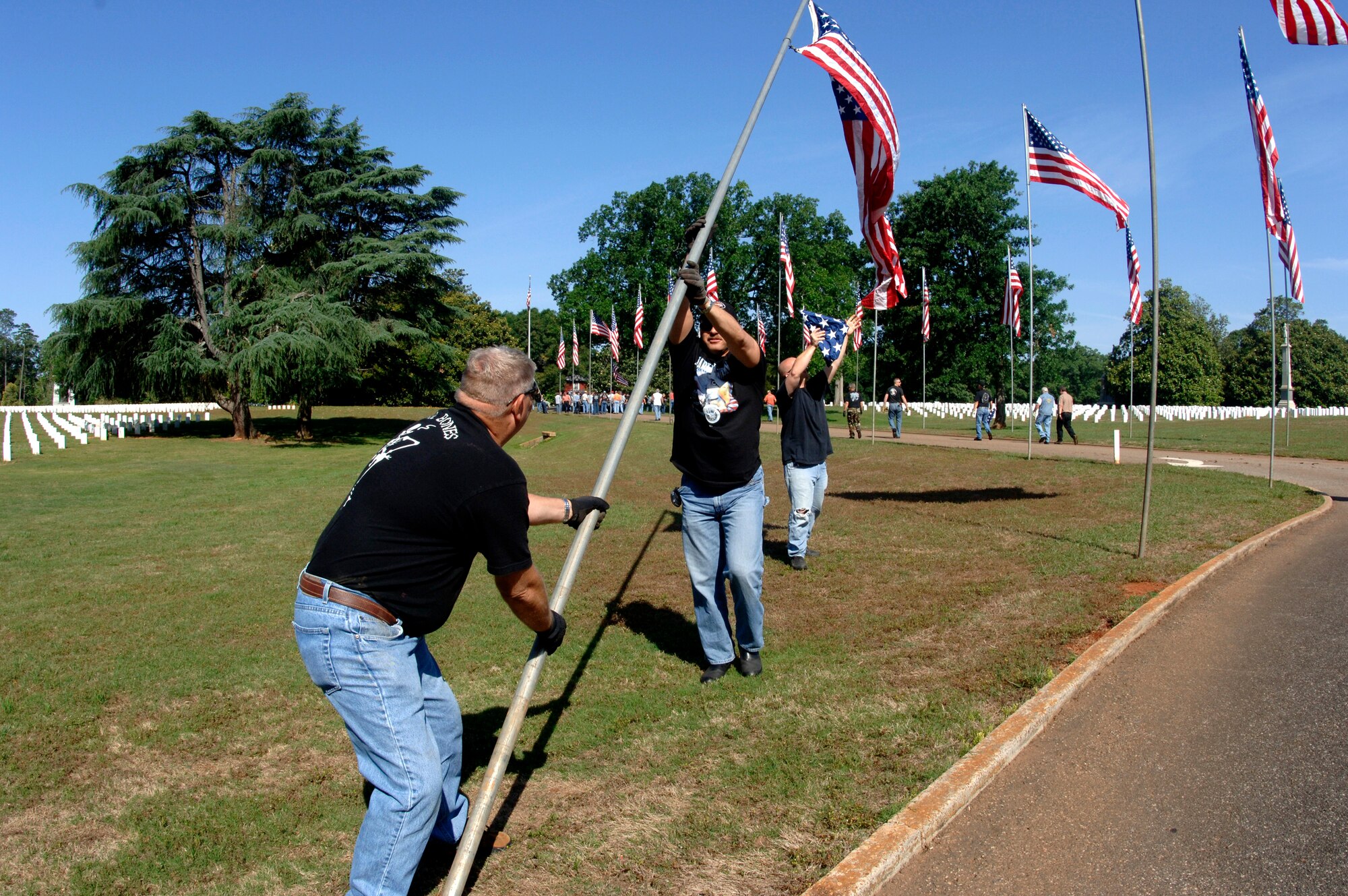 (From left) Chief Master Sgt. Richard Patterson, Senior Master Sgt. Charles Bynum and Staff Sgt. Phil Russell set up a U.S. flag at Andersonville National Cemetery near Americus, Ga., on Friday, May 19, 2006.  They were part of a group of 70 motorcycle enthusiasts from Robins Air Force Base, Ga., who volunteered to set up U.S. flags for Memorial Day.  The group rode as a convoy on the 50-mile trip.  Chief Patterson and Sergeants Bynum and Russell are with the 116th Air Control Wing.  (U.S. Air Force photo/Senior Master Sgt. Tom McKenzie) 