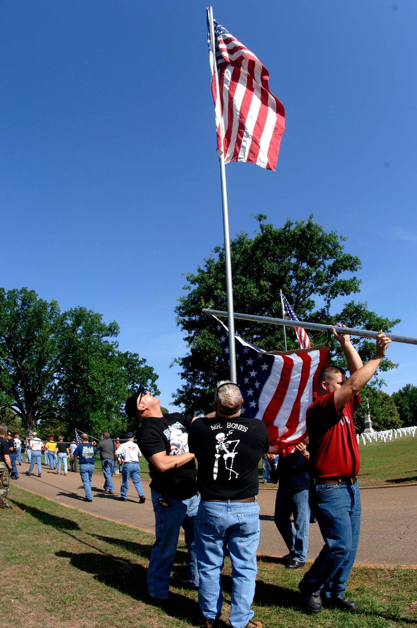 Senior Master Sgt. Charles Bynum and Chief Master Sgt. Richard Patterson (in black T-shirts) raise a U.S. flag at Andersonville National Cemetery near Americus, Ga., on Friday, May 19, 2006.  The two were part a group of 70 motorcycle enthusiasts from Robins Air Force Base, Ga., who volunteered to set up U.S. flags for Memorial Day.  The group rode as a convoy on the 50-mile trip.  Sergeant Bynum and Chief Patterson are from the 116th Air Control Wing. (U.S. Air Force photo/Senior Master Sgt. Tom McKenzie) 