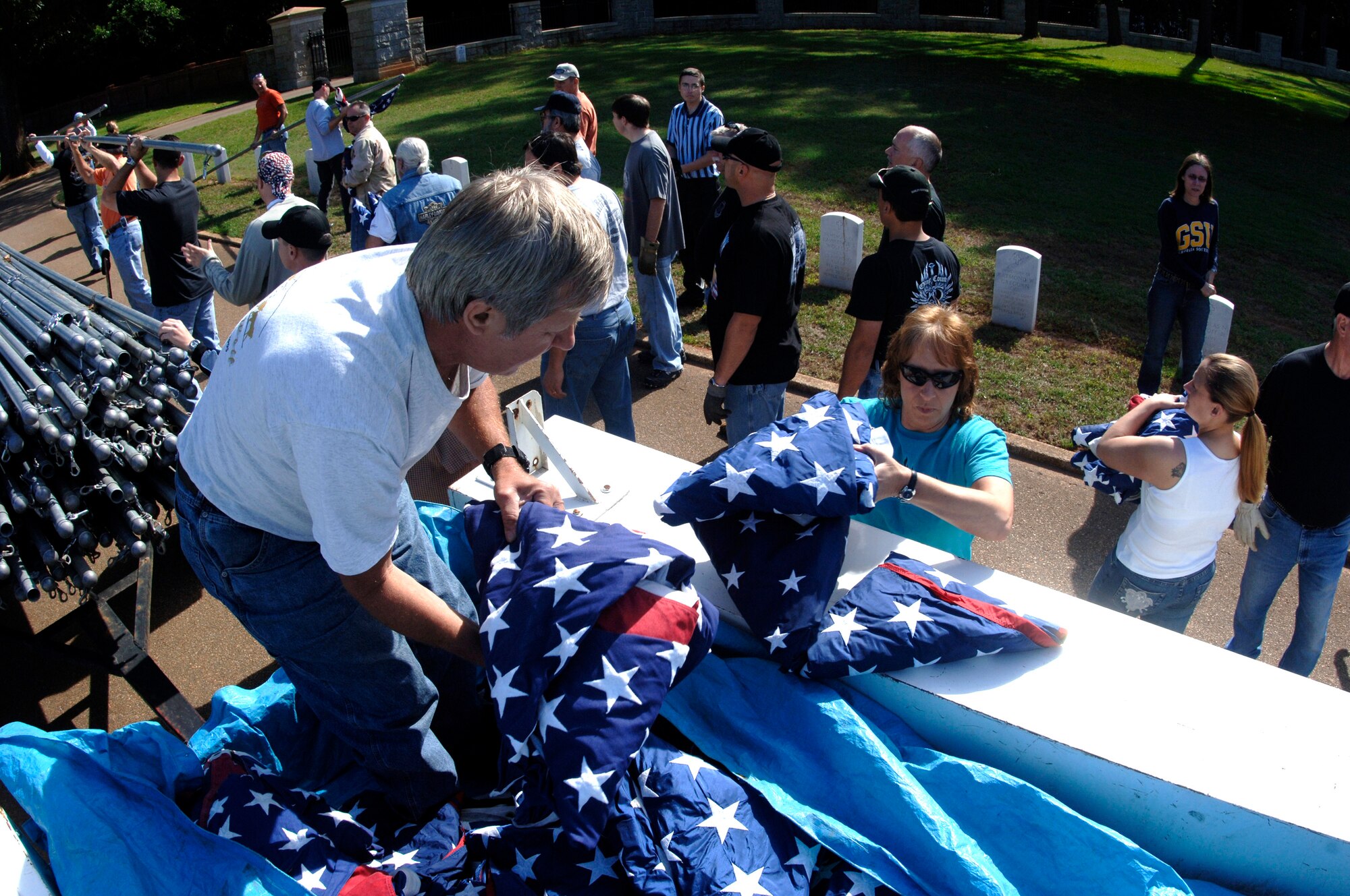 A volunteer at Andersonville National Cemetery near Americus, Ga., hands out U.S. flags to some 70 motorcycle enthusiasts from Robins Air Force Base, Ga., on Friday, May 19, 2006.  The group rode as a convoy on the 50-mile trip to the cemetery to set up the flags for Memorial Day.  (U.S. Air Force photo/Senior Master Sgt. Tom McKenzie)
