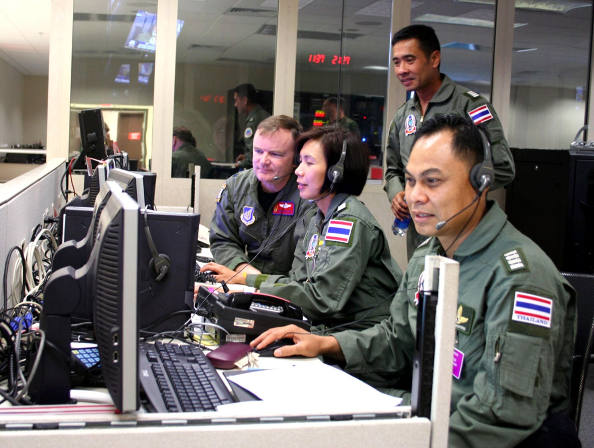 Lt. Col. Curt Walker (left), Wing Commander Sumana Chulamokha, Group Capt. Suwit Wattanaroek (standing) and Group Capt. Noi Parkperm coordinate air operations at the Gen. George C. Kenney Headquarters during the 25th annual Cobra Gold exercise on Tuesday, May 23, 2006. The exercise is hosted by Thailand at Hickam Air Force Base, Hawaii, from May 15 to 26. It demonstrates the planning, execution and reach-back capabilities the headquarters can provide in a contingency. Colonel Walker is with the combat operations division at Kenney Headquarters and the three Thai officers are with the Royal Thai Air Force. (U.S. Air Force photo/Capt. Yvonne Levardi)
