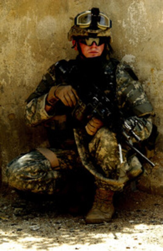 U.S. Army Pfc. Chris Smith secures a perimeter while his patrol leader talks to local Iraqi citizens during a patrol through the streets of Ameriah, a suburb of Baghdad, Iraq, on May 21, 2006. Smith is assigned to Alpha Company, 1st Battalion, 87th Infantry Regiment, 10th Mountain Division. 