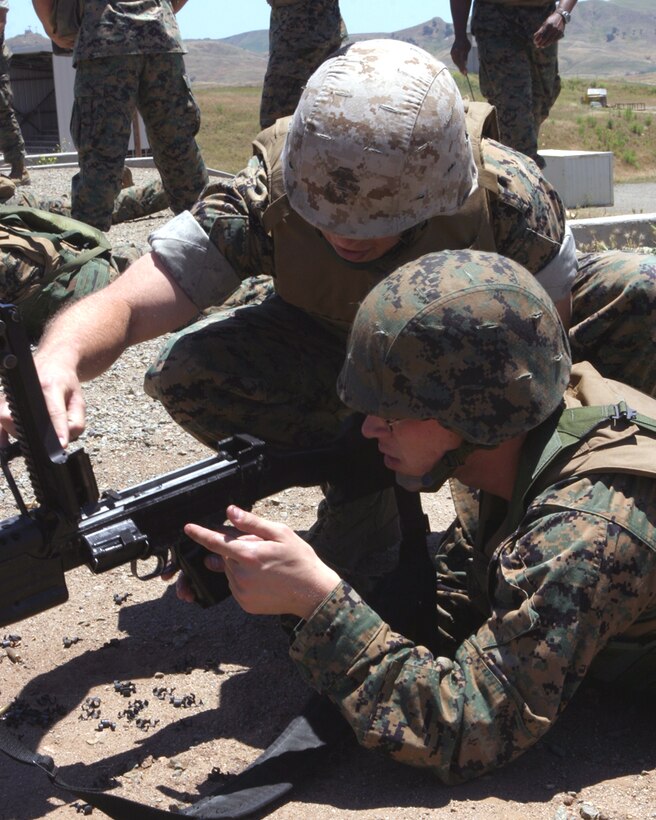 CAMP PENDLETON Calif. (May 24, 2006) --  CWO 2 Oscar P. Chaney, Nuclear, Biological, and Chemical officer with the 15th Marine Expeditionary Unit, helps Cpl. James B. Weaver, a field radio operator, with a M249 squad automatic weapon during a live fire exercise at Range 223 here. 15th MEU Marines are participating in the training to familiarize themselves with the weapon, and become more efficient in its maintenance and operation.