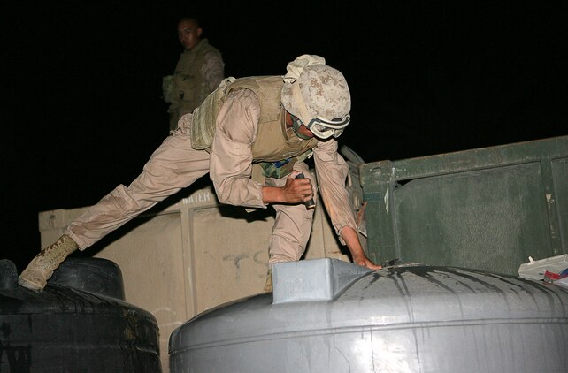 Taking a peak at the levels of a water container, Lance Cpl. Paul W. Schwartz, a 21-year-old native of Meridian, Idaho, with Combat Logistics Company 115, re-supplies a Marine outpost around Fallujah with fresh water May 24, 2006. Schwartz and the rest of Combat Logistics Battalion 5 serve as a logistical support unit in the Al Anbar Province, supporting American and Iraqi forces operating here. On major re-supply convoys, CLC 115 will deliver food, water, fuel and other equipment or supplies to multiple locations in one trip outside the security of Camp Fallujah.