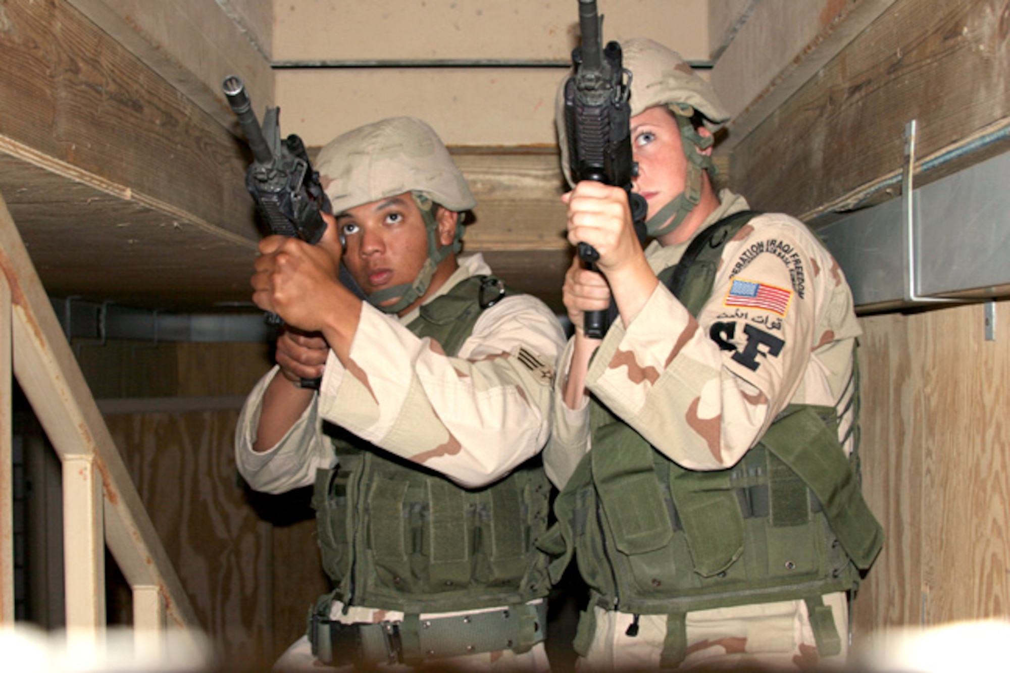 Senior Airmen Paris Carman (left) and Ravin Coulon move up the stairs of a simulated Iraqi home during "military operations in urban terrain" training on Friday, May 19, 2006, in Southwest Asia. (U.S. Army photo) 
