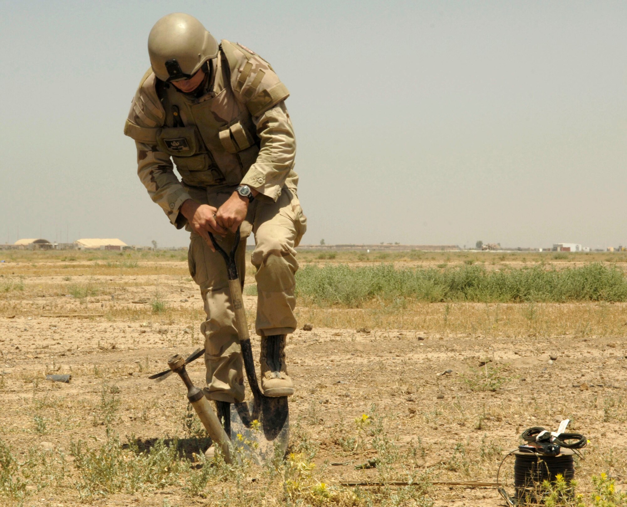 Senior Airman Scott Love digs near a 57mm rocket to loosen the dirt, enabling him to pull the rocket out of the ground at Balad Air Base, Iraq, on Monday, May 22, 2006. Airman Love is deployed to the 332nd Expeditionary Civil Engineer Squadron from Beale Air Force Base, Calif. (U.S. Air Force photo/Airman 1st Class Andrew Oquendo)
