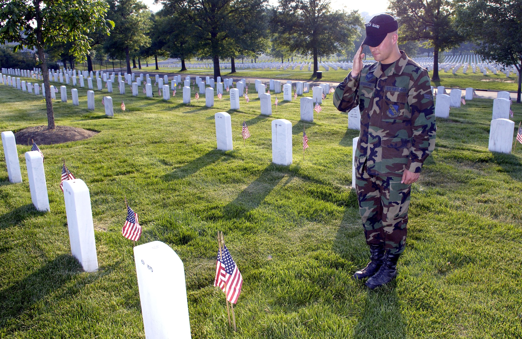 Airman 1st Class Dustin Woodford renders honors after placing a flag in front of his father's headstone at Arlington National Cemetery on Thursday, May 25, 2006. Airman Woodford is assigned to Bolling Air Force Base, Washington, D.C., and is a member of the United States Air Force Honor Guard Drill Team. He joined hundreds of Soldiers, Sailors, Airmen and Marines to place more than 227,000 flags at the cemetery. (U.S. Air Force photo/Master Sgt. Jim Varhegyi)