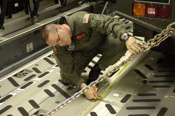 HICKAM AIR FORCE BASE, Hawaii -- Master Sgt. Mike Cumberland, a C-17 loadmaster with the 535th Airlift Squadron, Hickam AFB Hawaii, measures a tie-down chain to ensure a Halvorsen aircraft pallet loader is safely secured prior to a strategic airlift mission May 25.  Hickam sent two C-17s and approximately 25 personnel to assist the Australian Defense Force move personnel and equipment to Australia from the Solomon Islands to support peace operations in East Timor after continued unrest between East Timorese military forces and breakaway groups of police and military.  (U.S. Air Force Photo by Tech. Sgt. Shane Cuomo)