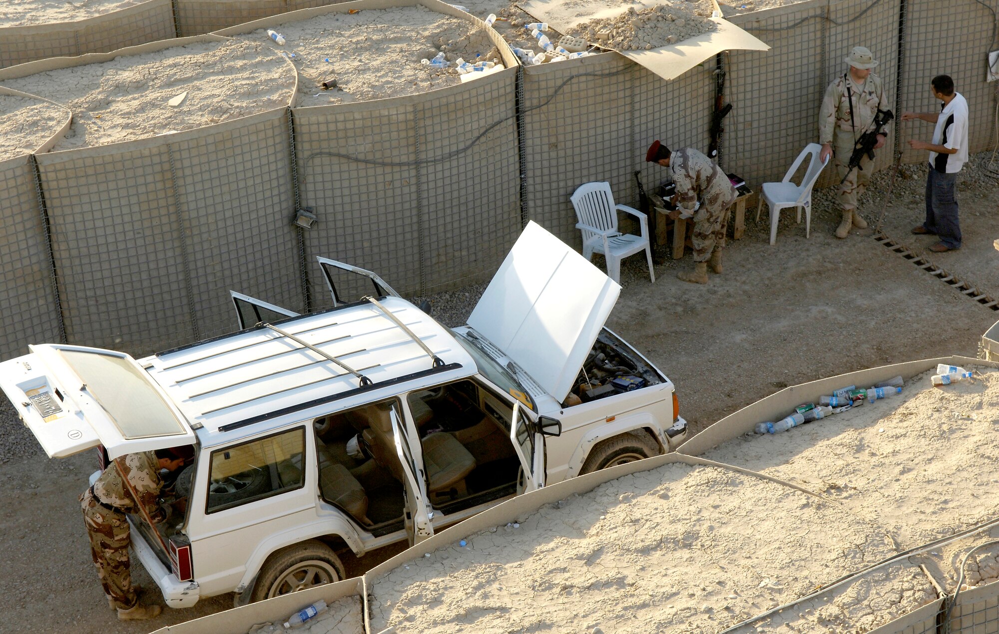 First Lt. Frank Bigelow watches as a vehicle is inspected by Iraqi soldiers before being cleared to enter the Ar Rasheed Base, Iraq, on Friday, May 26, 2006. More than 250 Iraqi soldiers make up the Iraqi base defense unit. Each soldier is trained and advised by five security forces Airmen and their Army commander who live and work on the base. Lieutenant Bigelow is the assistant team chief of Base Defense Unit Team 3602. (U.S. Air Force photo/Senior Airman Brian Ferguson)