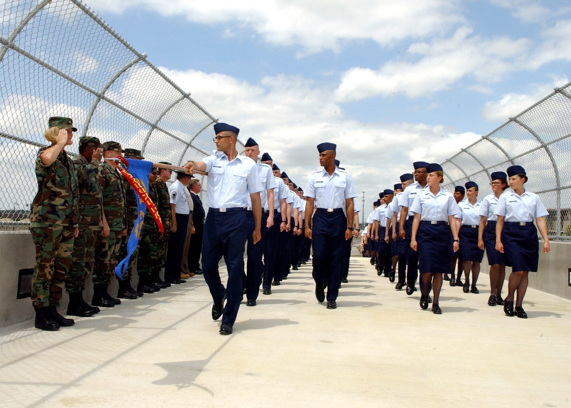 Brig. Gen. Mary Kay Hertog salutes basic military training flights 407 and 408 of the 322nd Training Squadron as they pass in review over the new troop crosswalk at Lackland Air Force Base, Texas, on Thursday, May 25, 2006. The flights were the first to use the new bridge that will alleviate congestion and increase safety for troop movement.  General Hertog is commander of the 37th Training Wing at Lackland AFB. (U.S. Air Force photo/Alan Boedeker)            