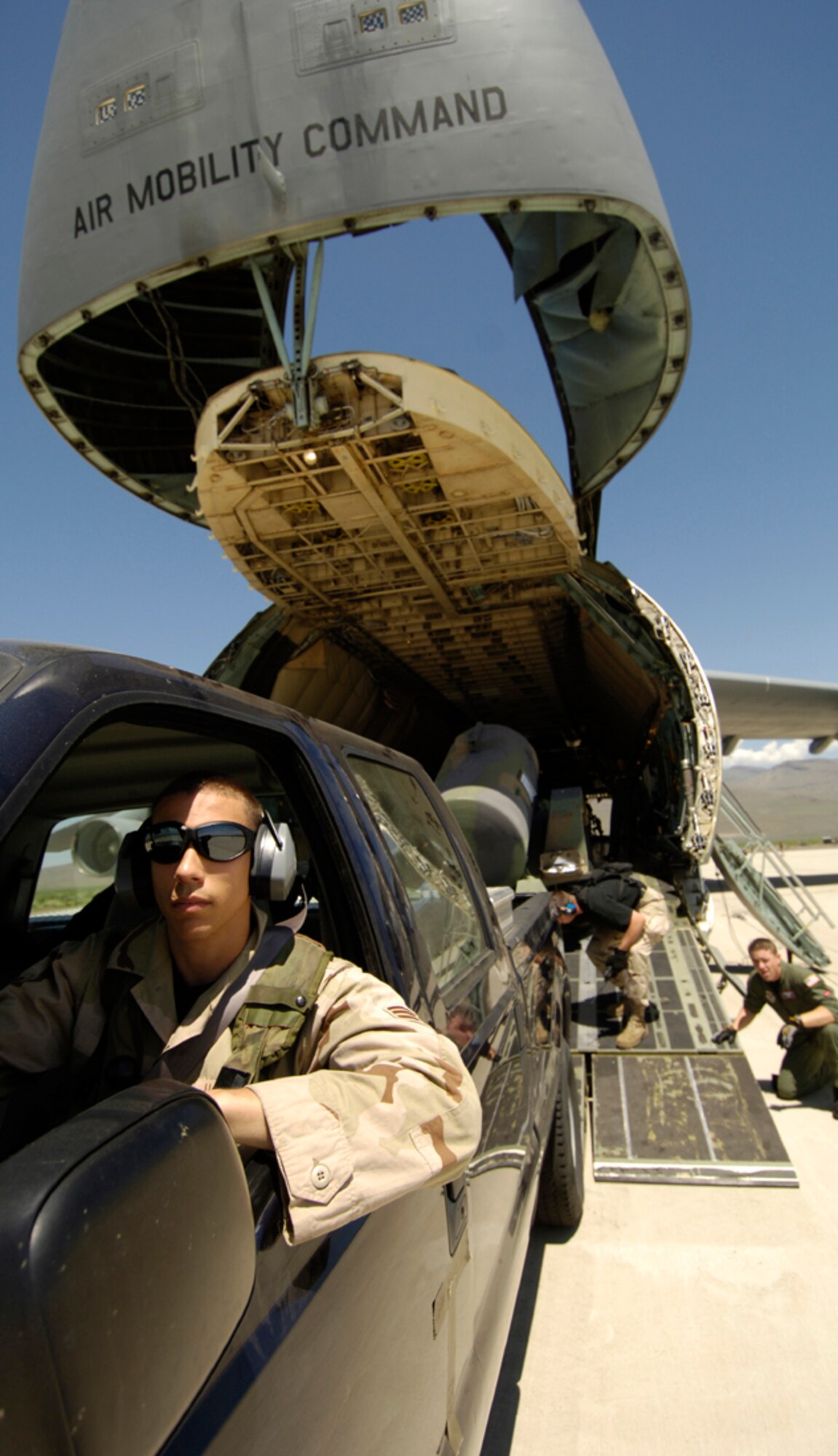 A member of the 615th Contingency Response Group drives a government vehicle towing a water tank off a C-5 Galaxy as part of exercise Lightning Fury, a staged airfield seizure held at Amedee Field, Herlong, Calif., May 16. (U.S. Air Force photo by Staff Sgt. James  Harper Jr.)
