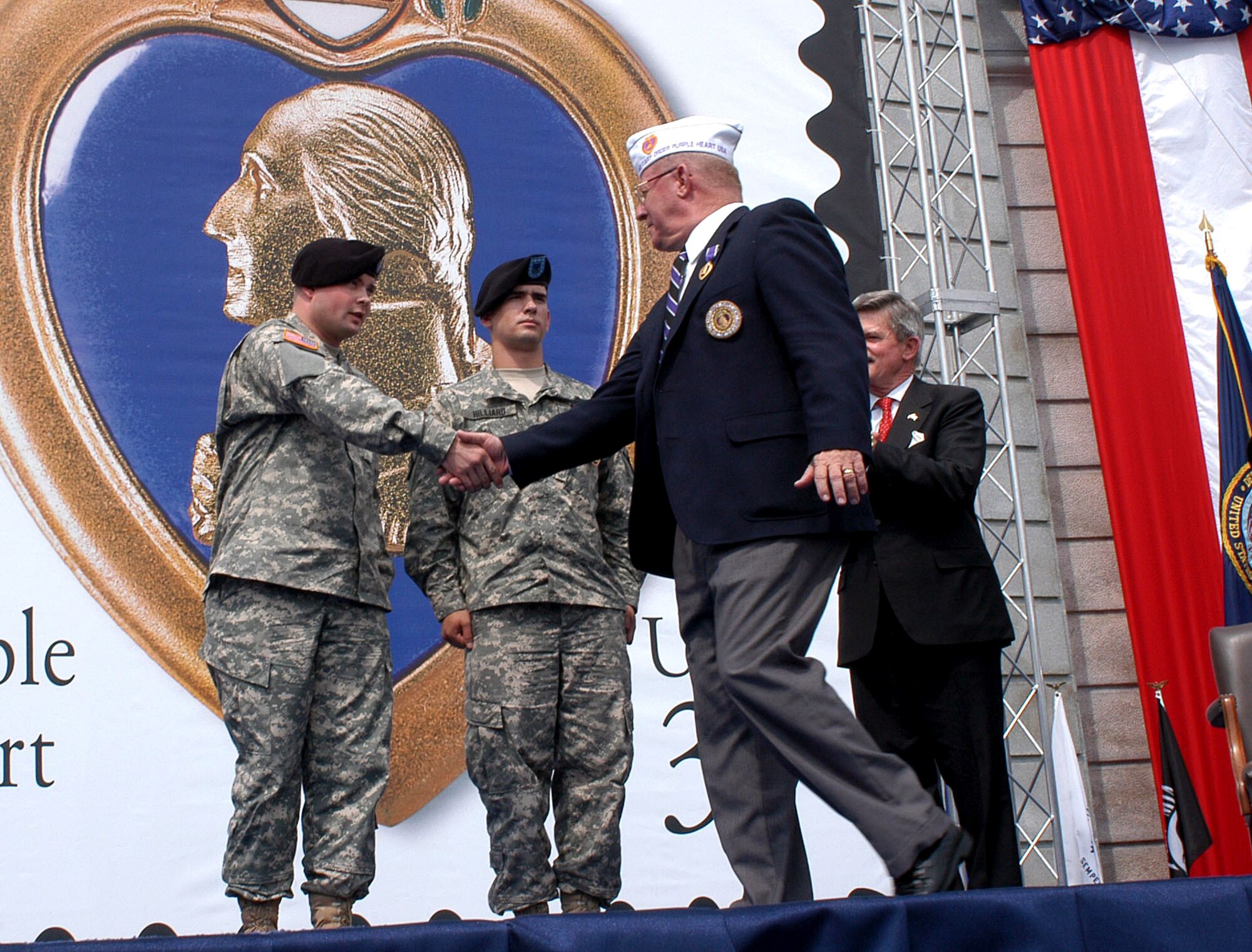James Randles, national commander of the Military Order of the Purple Heart, congratulates Army Spc. Michael Hilliard and Army Spc. Ian Wagner after they received their Purple Hearts at Arlington National Cemetery on Friday, May 26, 2006. The presentation was part of the issuance ceremony for the new version of the Purple Heart definitive stamp. (U.S. Army photo/Sgt. Sara Wood) 
