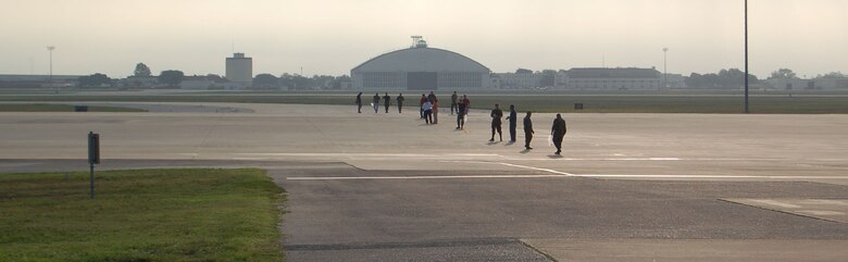 Alamo Wing members walk the line in the early morning light. Awareness of Foreign Object Damage potentials increased wing-wide participation in prevention programs including events like FOD walks. Foreign objects can be loose bolts, washers, wire and even partes of the concrete or the ramp the aircraft are parked on.  (U.S. Air Force photo by Tech. Sgt. Collen McGee, 433rd Airlift Wing Public Affairs)