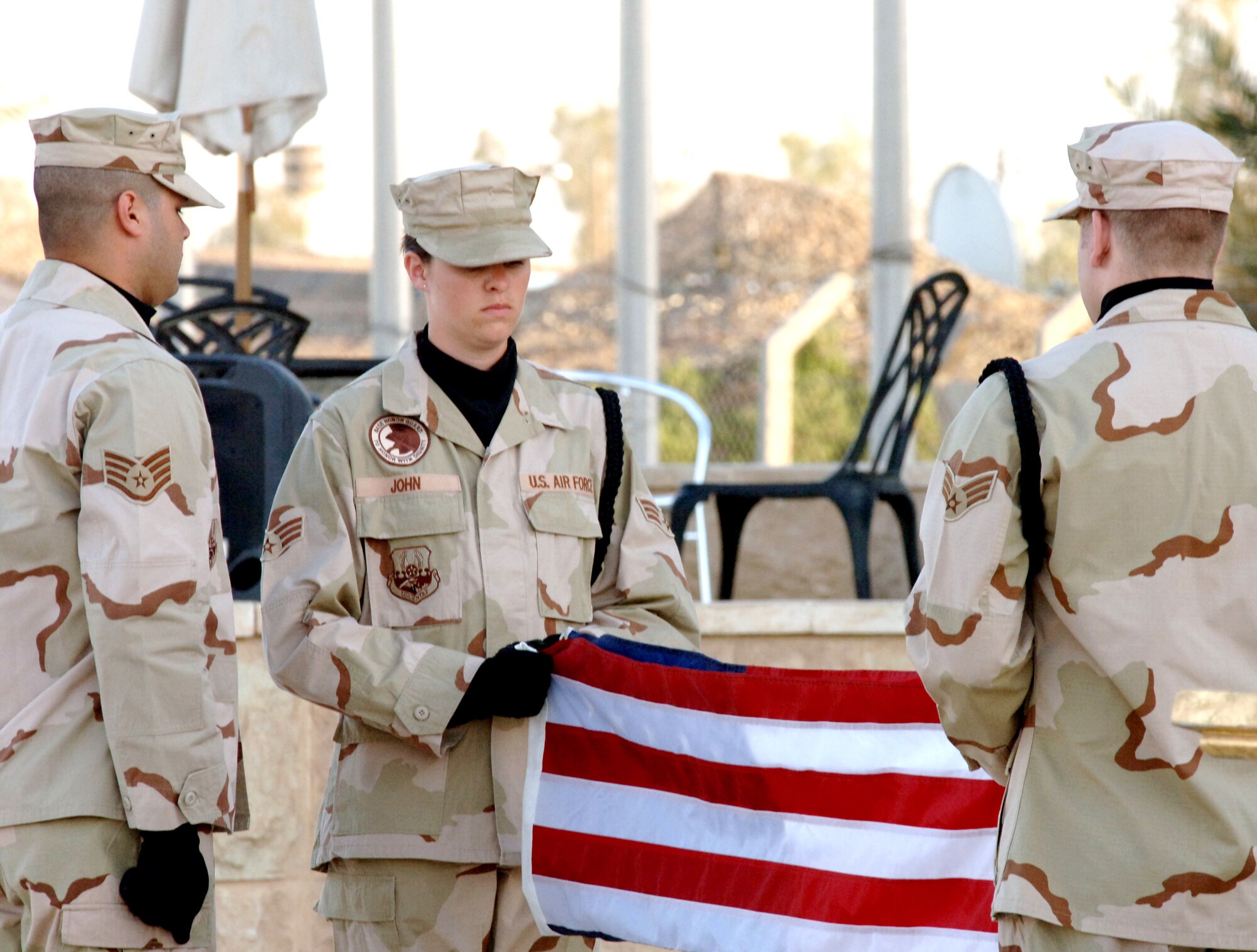 An honor guard from the 447th Air Expeditionary Group folds the flag during the Memorial Day retreat ceremony at Sather Air Base, Iraq, on Monday, May 29, 2006. From left are Staff Sgt. Jimmy Roman and Senior Airmen Peyton John and Dennis Maser. The 447th AEG operates the primary aerial port for transient military aircraft entering and exiting Iraq. The base is named in honor of Staff Sgt. Scott Sather, a Clio, Mich., native who was killed in combat in Iraq on April 8, 2003. (U.S. Air Force photo/Staff Sgt. Bryan Bouchard)
