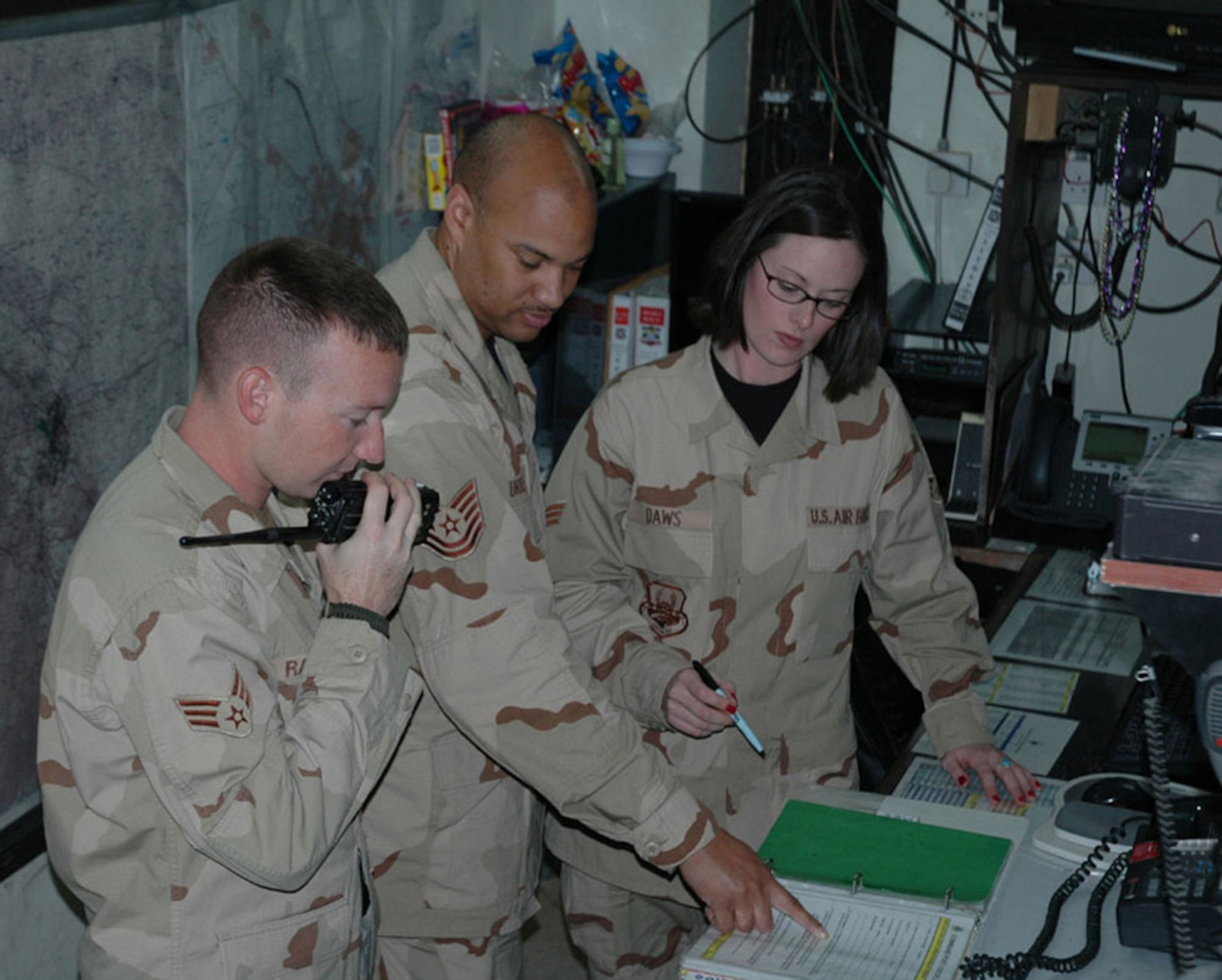 Senior Airmen Christ Ramsuer and Abby Daws, deployed from Shaw, perform turnover with Tech. Sgt. Charles Murrell at the 506th Air Expeditionary Group Command Post.  (U.S. Air Force Photo/Staff Sgt. Kristina Barrett)