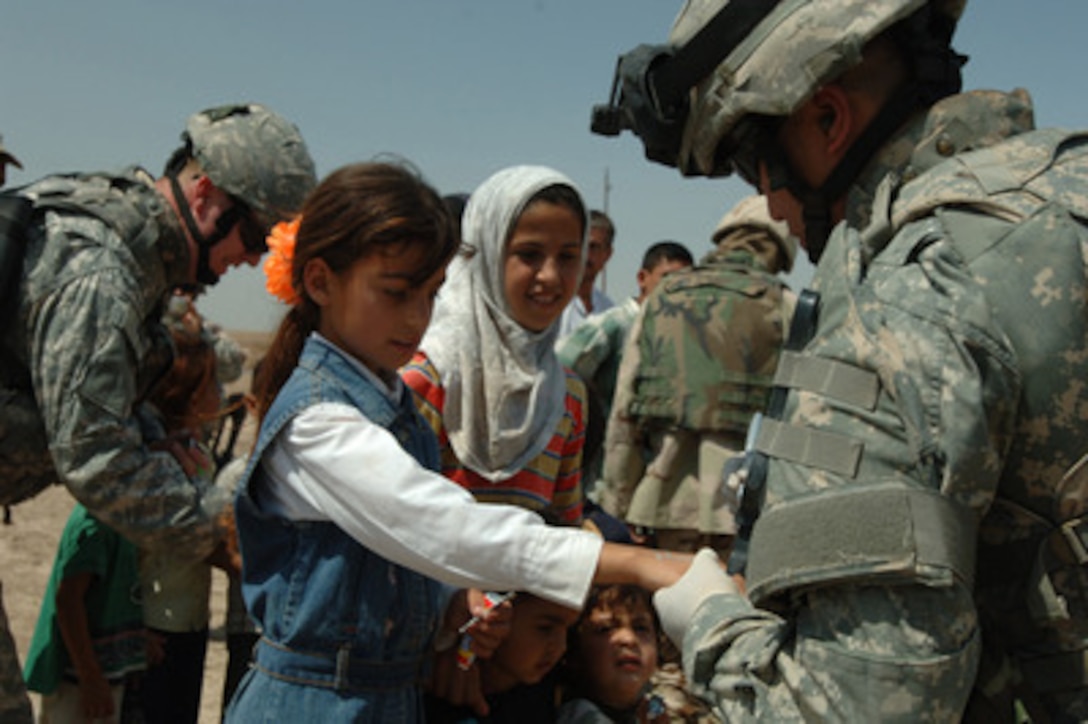U.S. Army Sgt. Karlo Endaya marks an Iraqi girl's hand to identify the medical care she requires during a medical operation near Baghdad, Iraq, on May 24, 2006. The medical operation is being conducted jointly with U.S. Army soldiers from Alpha Battery, 3rd Battalion, 6th Artillery Regiment and Iraqi army soldiers and is providing basic medical aid to the local community. 