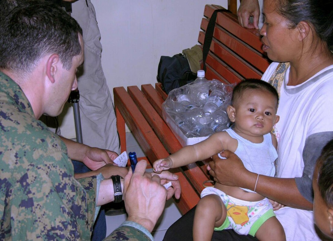 SEWON, Indonesia (May, 31, 2006) -- Navy Lt. Tim Ayers examines a 12-month-old Indonesian girl at a clinic established here today by III Marine Expeditionary Force Marines and sailors at the request of the Indonesian government following the May 27 earthquake that tore through the island of Java. The team of about 100 service members is providing surgical and acute care for victims. The infant was struck in the back by a falling brick during the earthquake. (Official U.S. Marine Corps photo by 1st Lt. Eric C. Tausch)