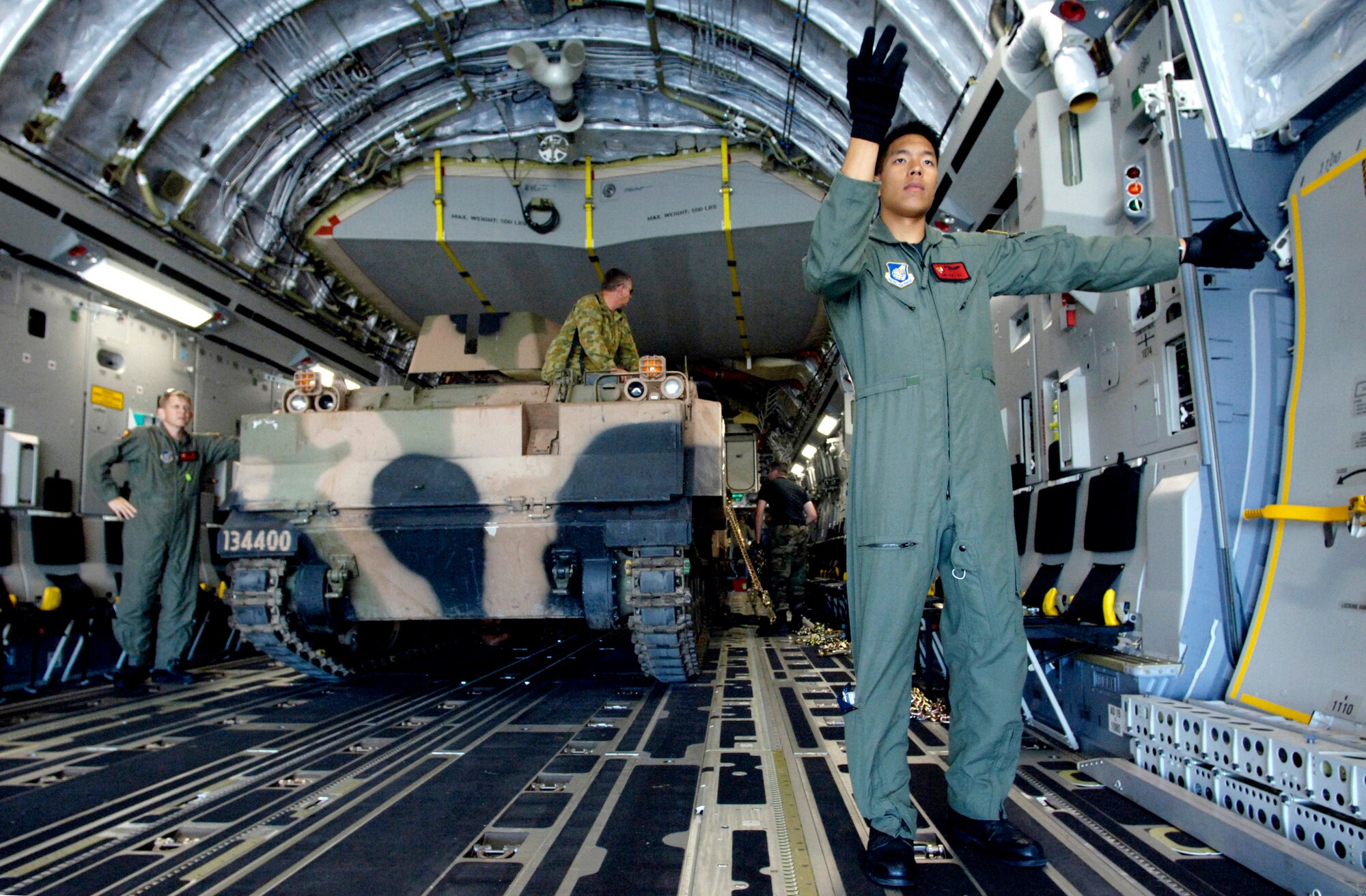 Airman James Ngo marshals in a second armored personnel carrier onto a C-17 Globemaster III at Royal Australian Air Force Base Townsville, Australia, on Tuesday, May 30, 2006. Two C-17s from the 15th Airlift Wing and the Hawaii Air National Guard's 154th Wing at Hickam Air Force Base, Hawaii, are helping the Australian Defense Force reposition its forces in Australia to better support peace operations in East Timor. Airman Ngo is assigned to the 535th Airlift Squadron. (U.S. Air Force photo/Tech. Sgt. Shane A. Cuomo) 