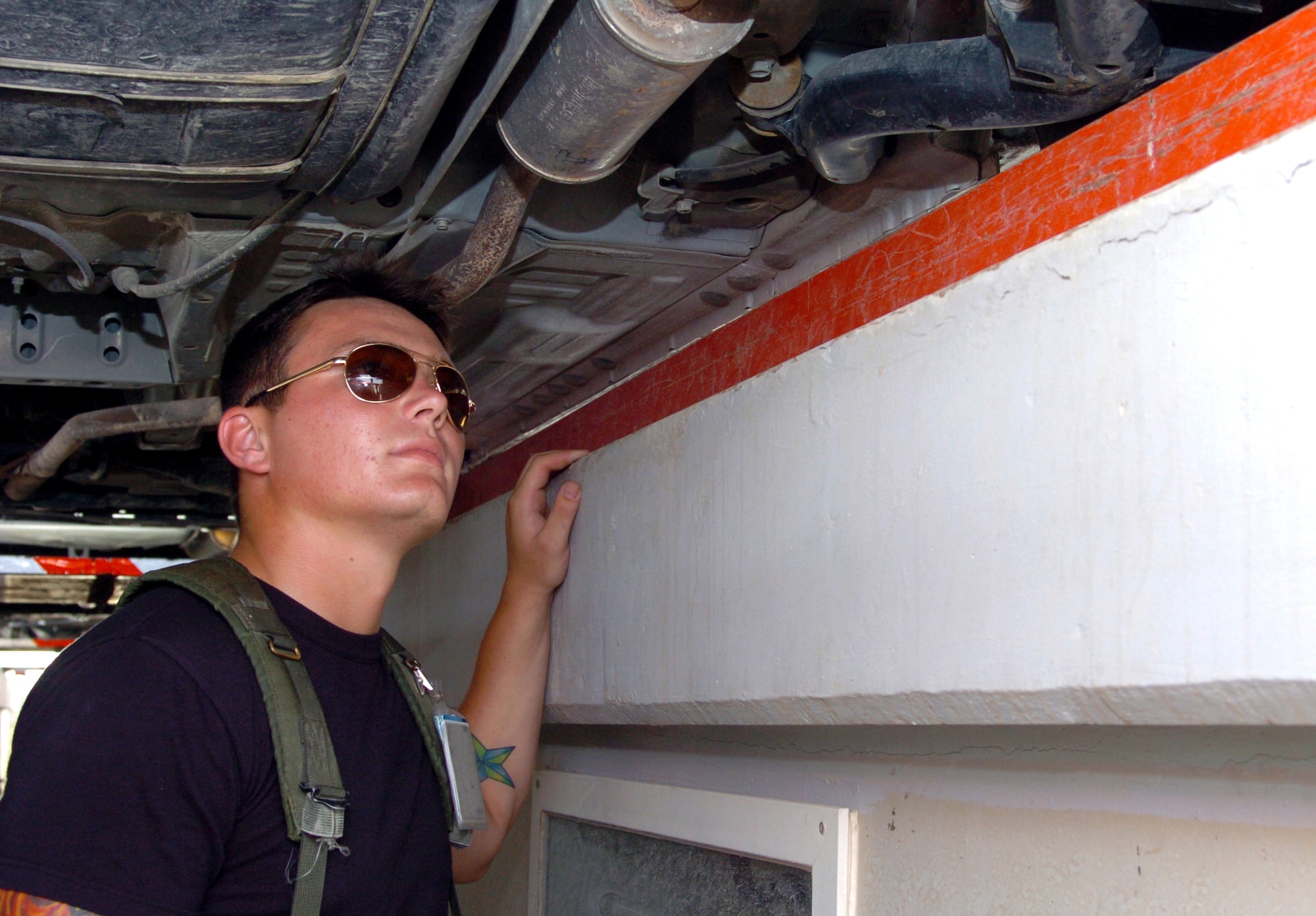 Airman 1st Class Justin Hopkins inspects the undercarriage of a vehicle in the Vehicle Search Area at a deployed location in Southwest Asia on Saturday, May 20, 2006. All vehicles must be cleared before being granted access to the base. Airman Hopkins is assigned to the 380th Expeditionary Security Forces Squadron, and is deployed from Scott Air Force Base, Ill. (U.S. Air Force photo/Master Sgt. Stan Coleman)
