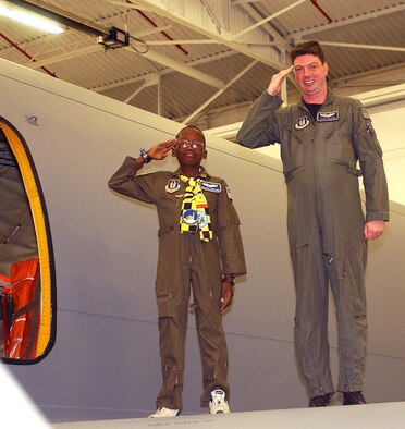 ANDREWS AIR FORCE BASE, Md. -- Michael Ogunjimi, 10, of Washington, D.C., joins Reservist Capt. Scott Clark, 756th Air Refueling Squadron pilot, to salute from the wing of a KC-135 Stratotanker Oct. 27. The 459th Air Refueling Wing and the District of Columbia Air National Guard 113th Wing teamed up to host the "Pilot for a Day" program. "P4D" is a community outreach program that allows military and civilian children of all ages who suffer from serious or chronic medical conditions to visit an installation for the day to tour wing and base facilities. (U.S. Air Force photo by Staff Sgt. Amaani Lyle)