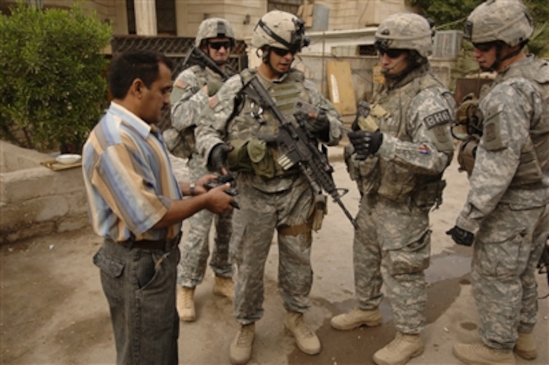 U.S. Army soldiers with Bravo Company, 4th Battalion, 23rd Infantry Regiment check an Iraqi civilian's weapon permit during a patrol in Baghdad, Iraq, Oct. 23, 2006.