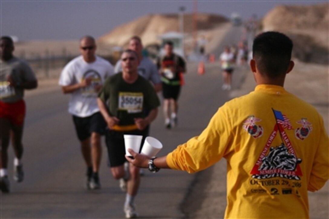 A volunteer servicemember hands water to runners of the first satellite Marine Corps Marathon hosted at Al Asad, Iraq, Oct. 29. The runners traveled from all across Iraq to participate in the event and will be added to the books as officially completing the stateside event.
