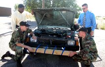 Four Kirtland Air Force Base team members participating in the Air Force Research Laboratory-sponsored Junior Workforce Challenge Project check under the hood of one of the automobiles the group has employed to test their vehicle-stopper prototypes. Team members are Jaton Wince (top left), 1st Lt. Kenneth McDougall (bottom left), Jack Massarello (top right) and Capt. Chris Rehm (bottom right). (Photo by Michael P. Kleiman)